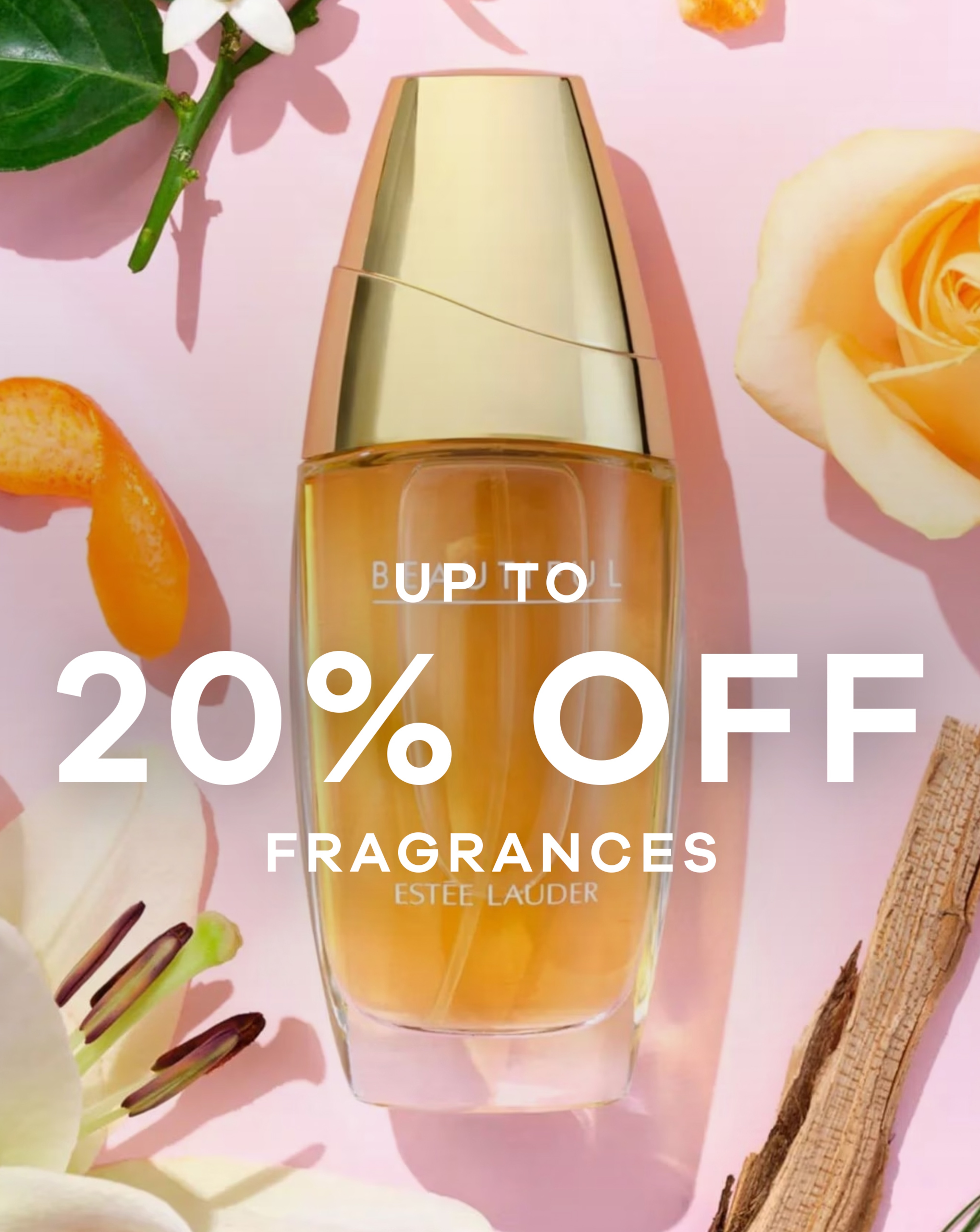 A perfume bottle on a pink background with flowers at the side of it.