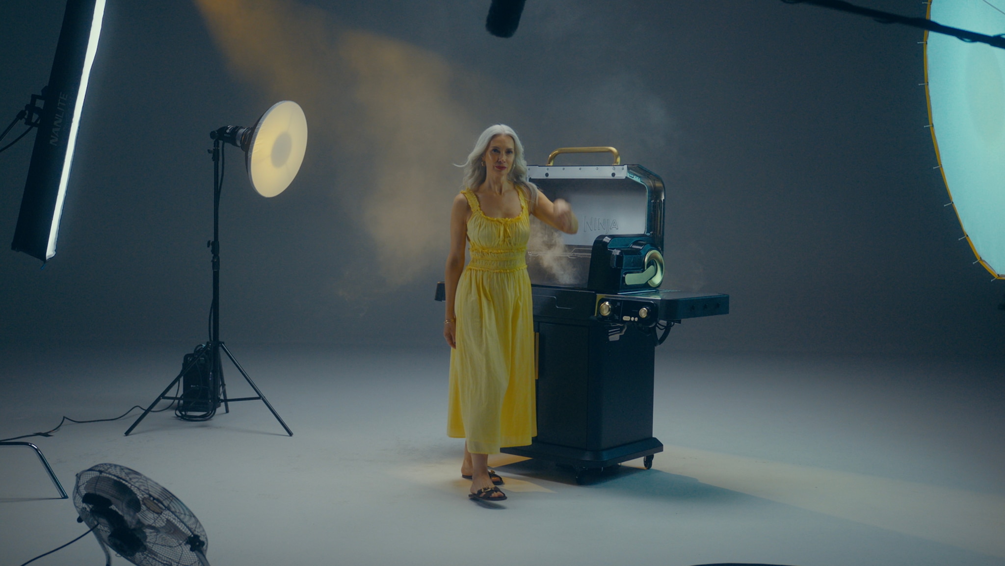A woman in a yellow dress stood next to a big barbeque
