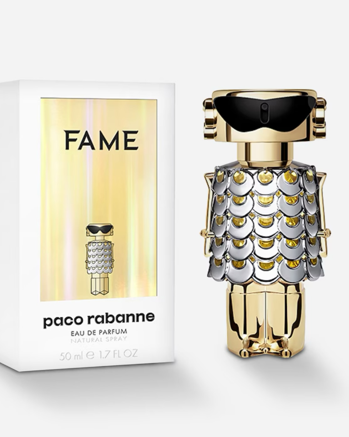 A bottle of Paco Rabanne fame eau de parfum next to its white and gold packaging, featuring a bottle shaped like a gold and silver robot wearing black sunglasses and a chainmail dress.