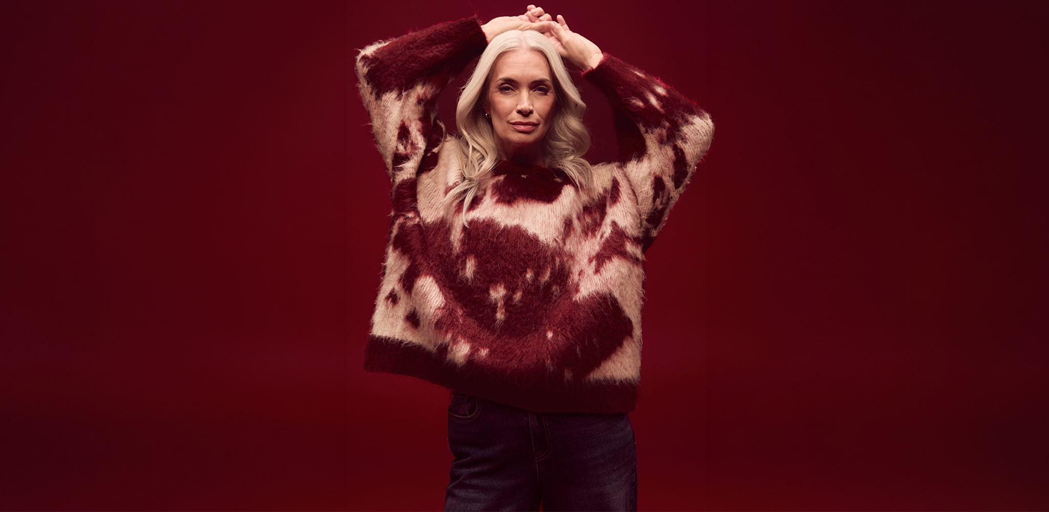 A woman wearing a pink and red animal print knitted jumper.