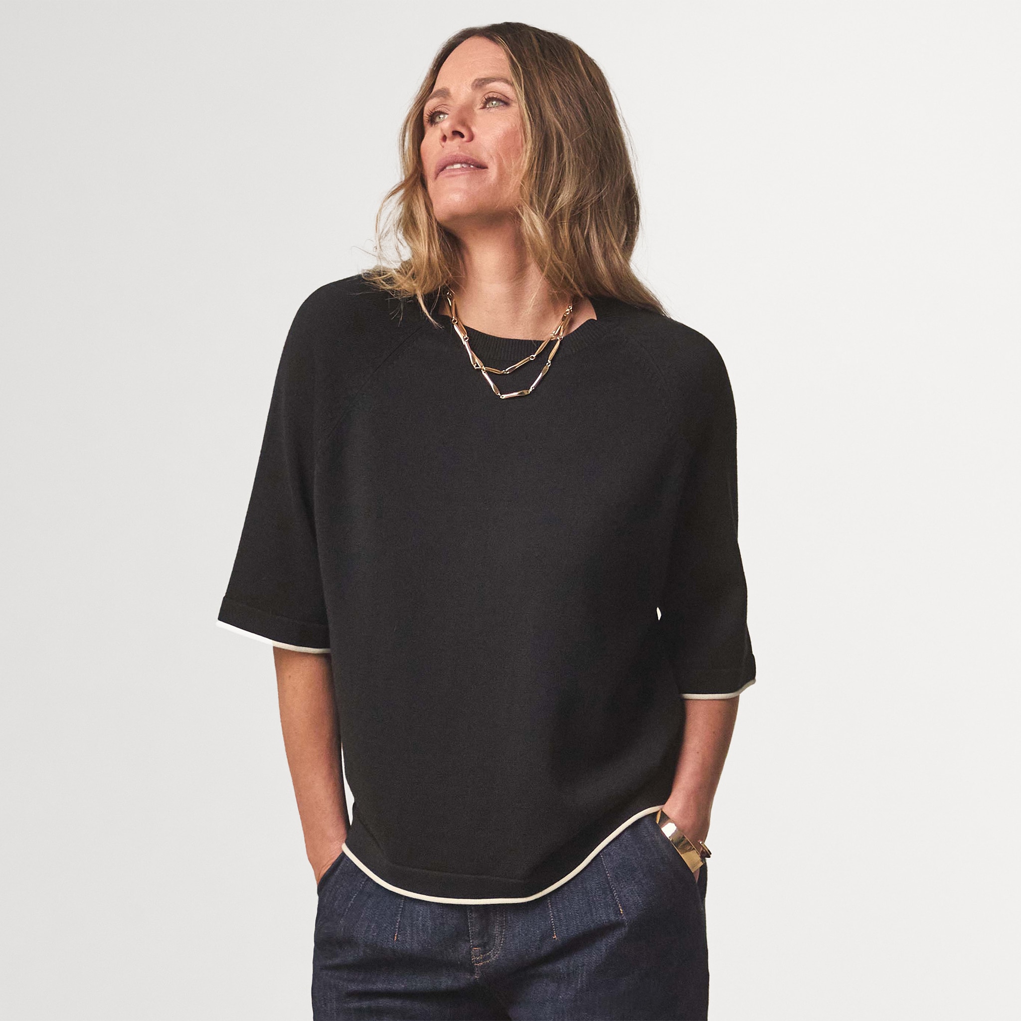 Lady wearing a black short sleeved jumper stood with her hands in her pocket
