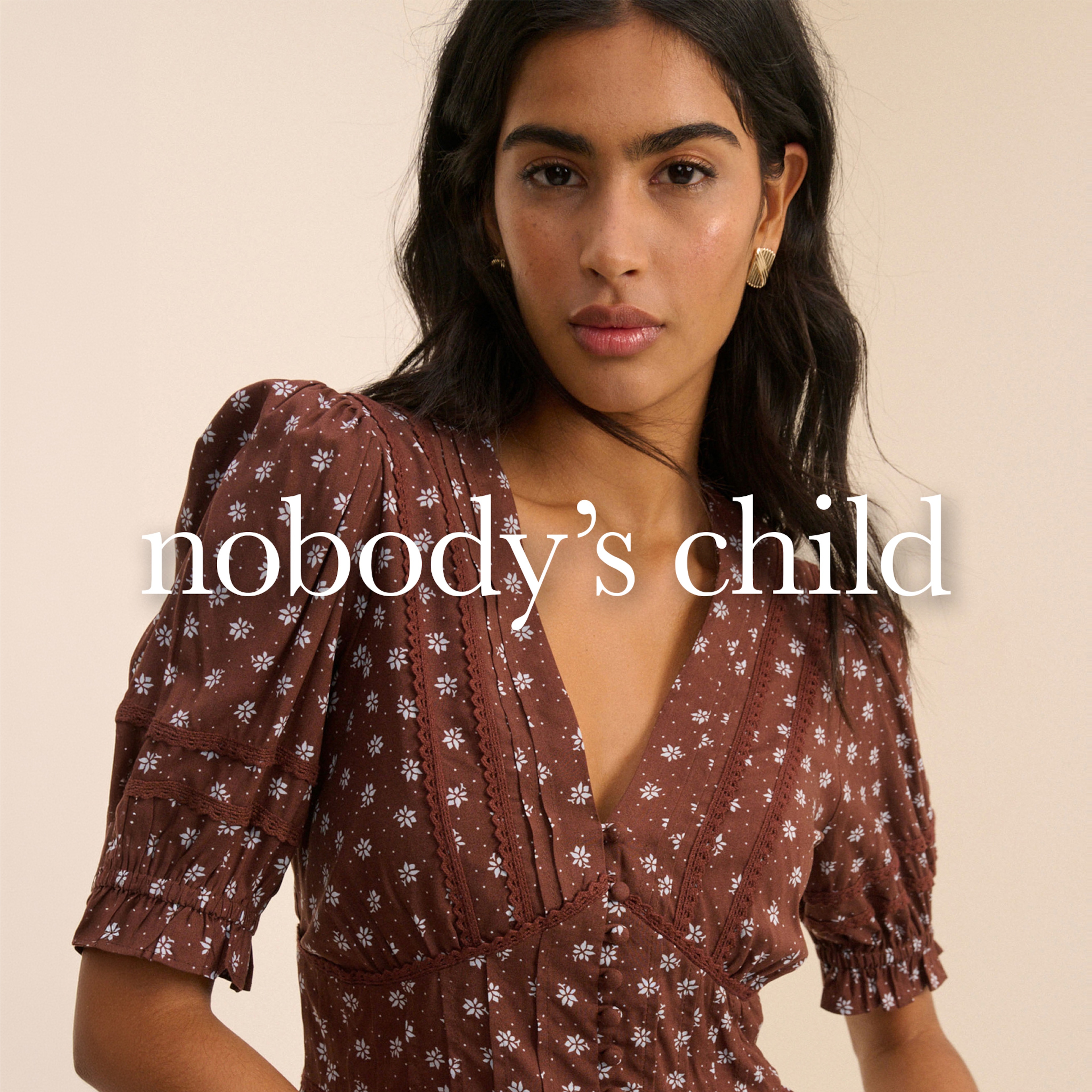 A woman wearing a nobody's child brown dress.