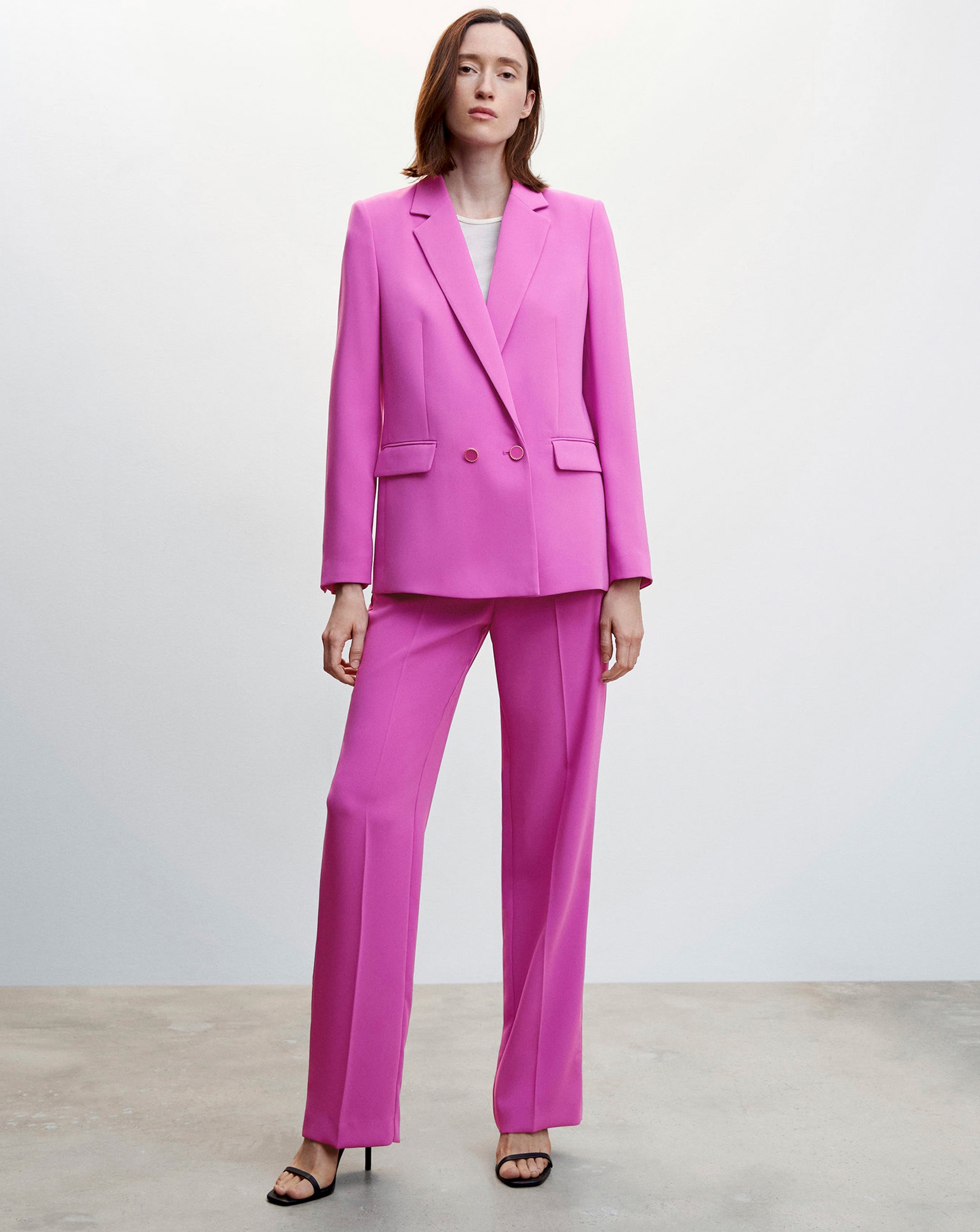 Person wearing a bright pink tailored suit with a blazer and straight leg trousers