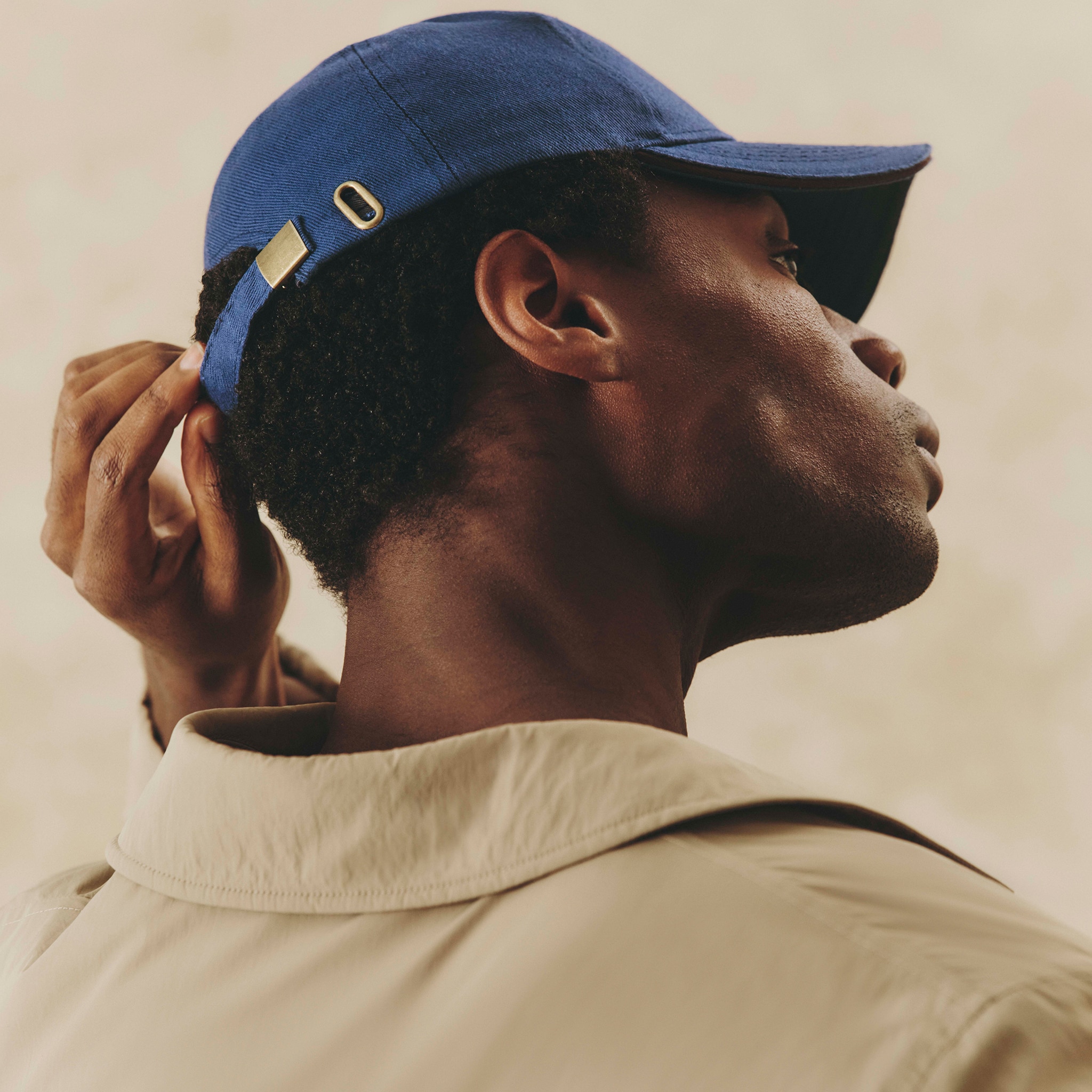 Model wears Stone Wadded Mac with blue baseball cap