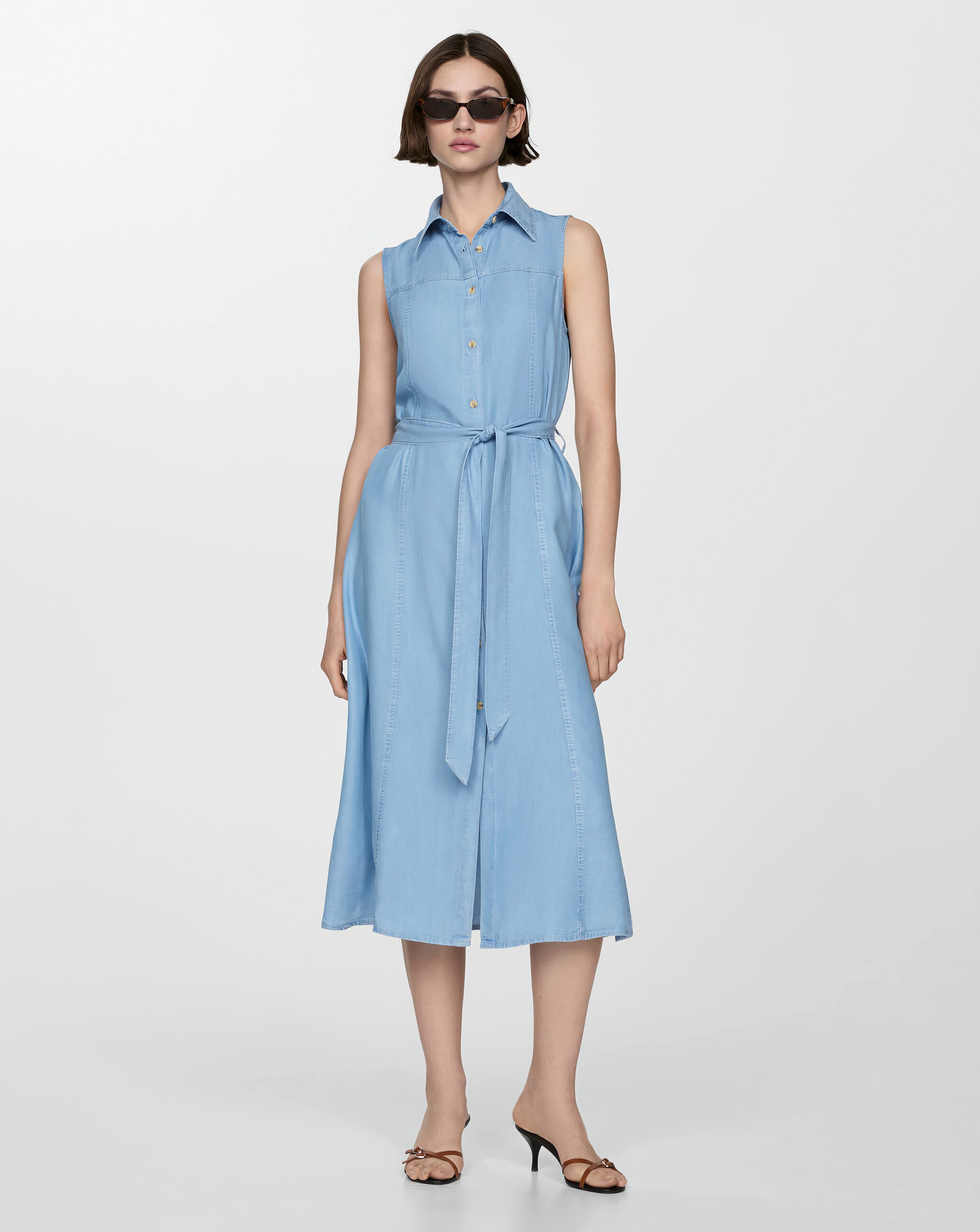 Person wearing a sleeveless light blue midi dress with buttons and a waist tie.