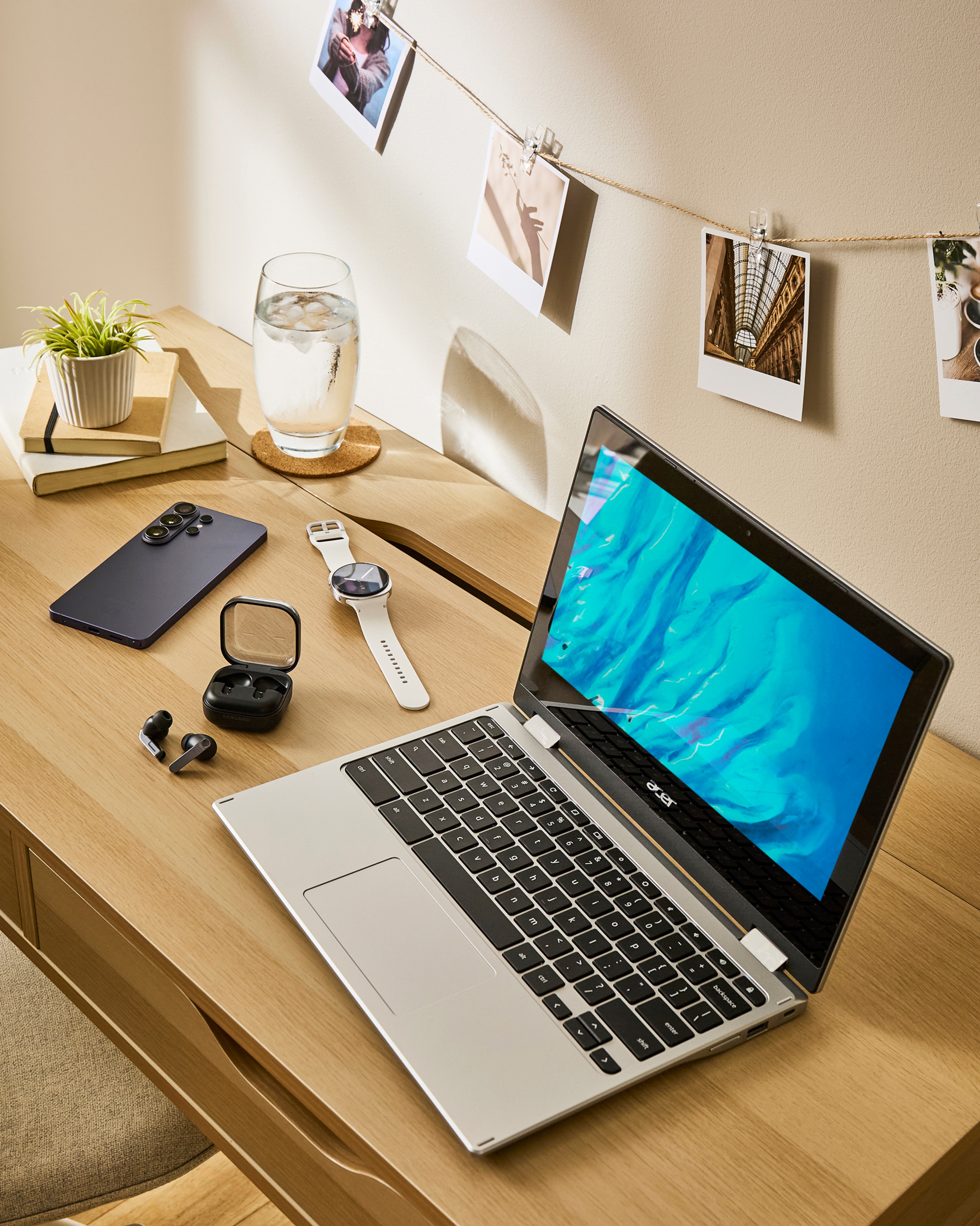 A desk with lots of tech on. A phone, ear buds, a smart watch and a laptop.