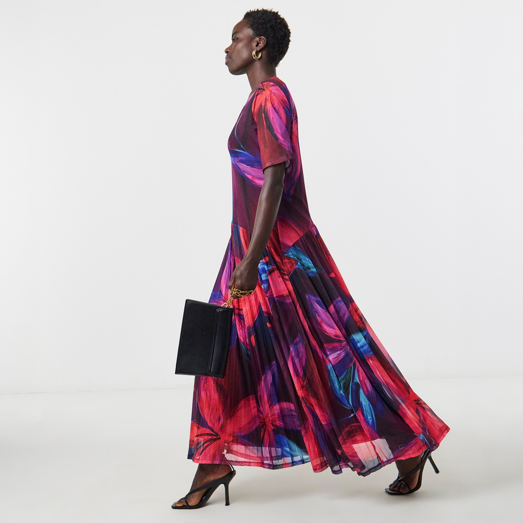 A woman walking wearing a colourful occasion dress.