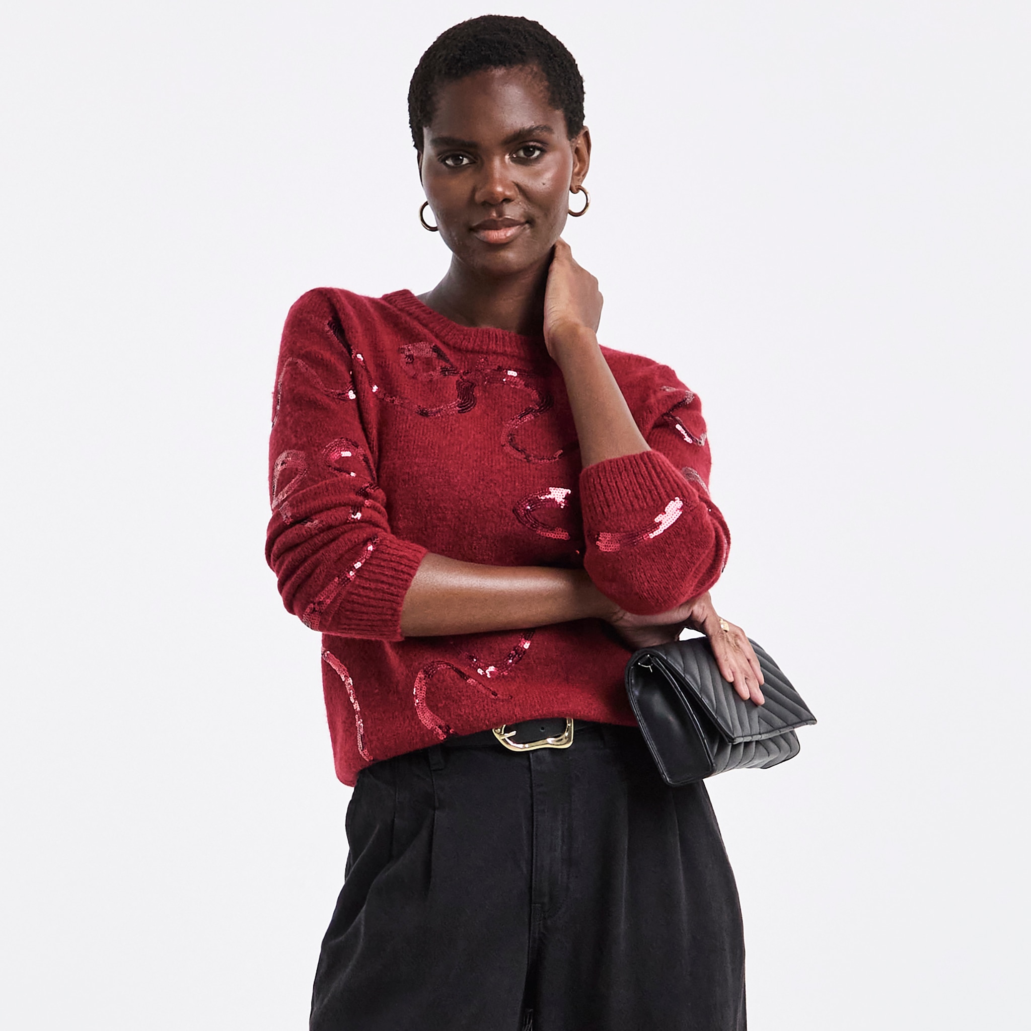 A woman wearing a red knitted jumper with sequins on.