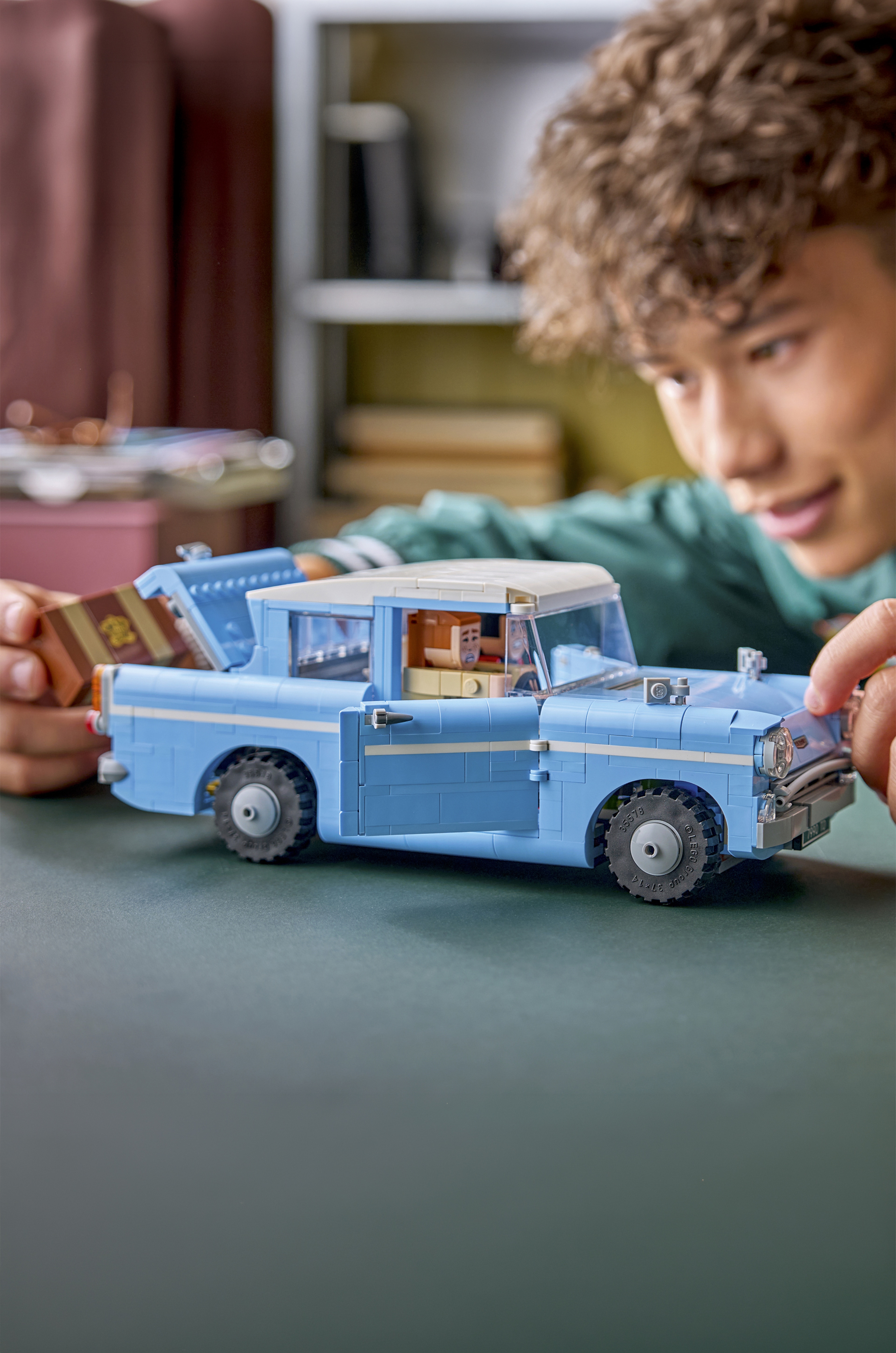 A person playing with a blue LEGO® car.
