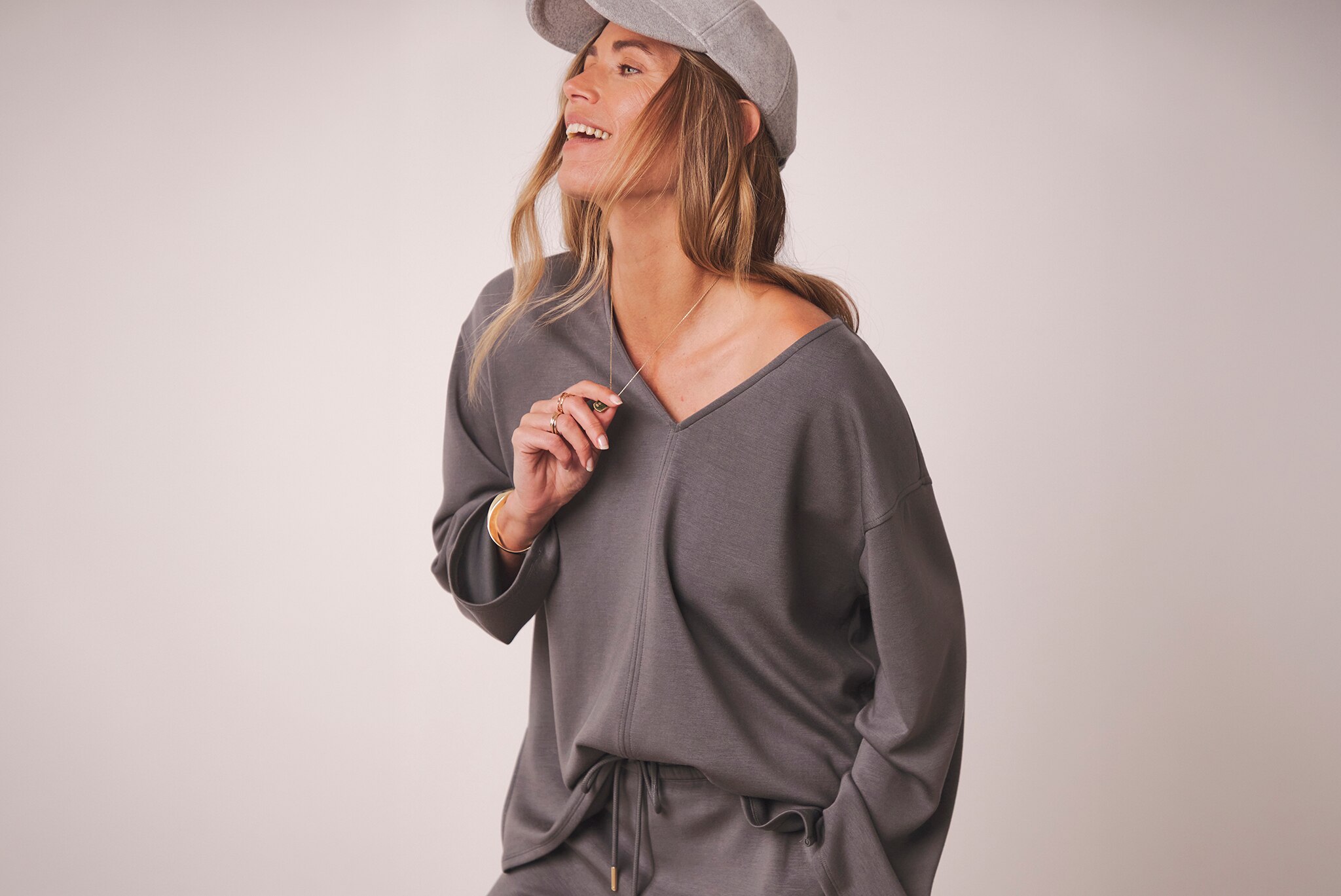 A woman wearing casual grey clothing with a cap looking to the left.
