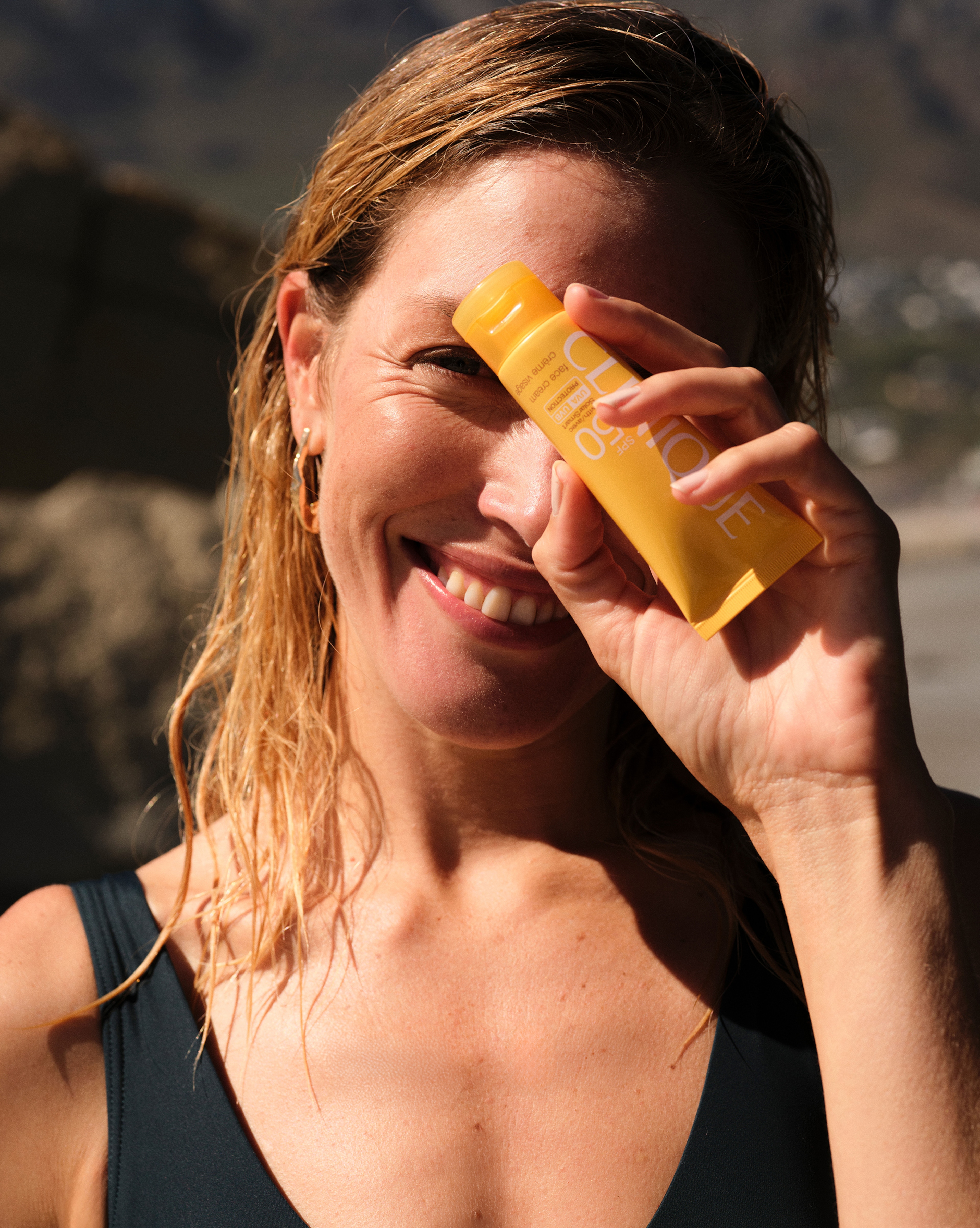 A lady holding up a beauty product in front of her face