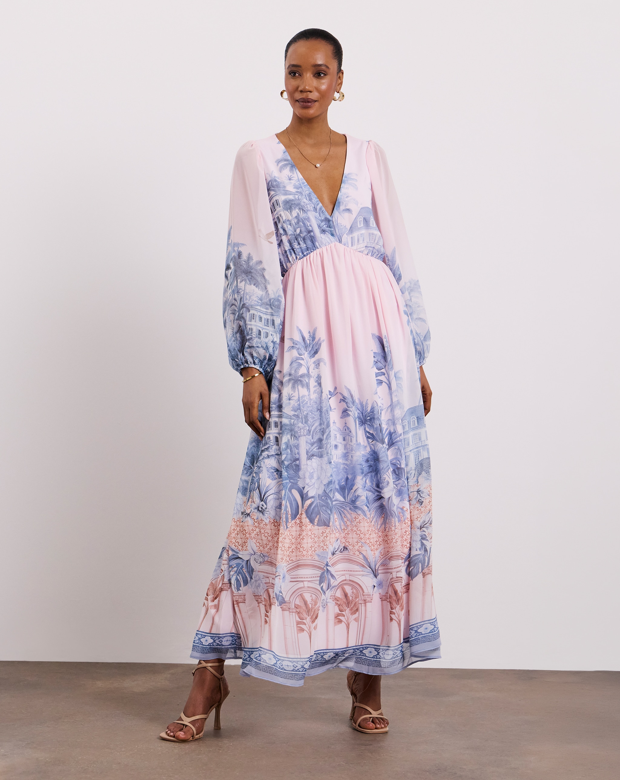 Person wearing a Joanna Hope pastel pink maxi dress and nude strappy heels.