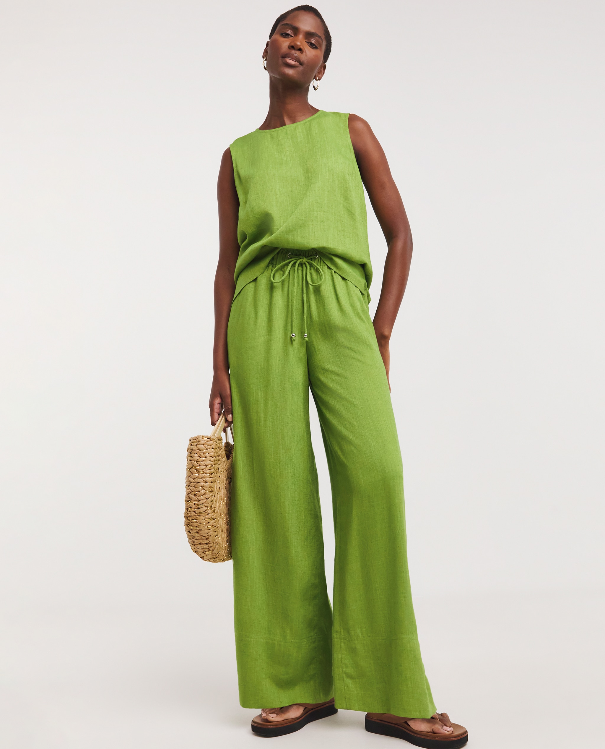Model is wearing a lime green linen top with matching linen trousers.