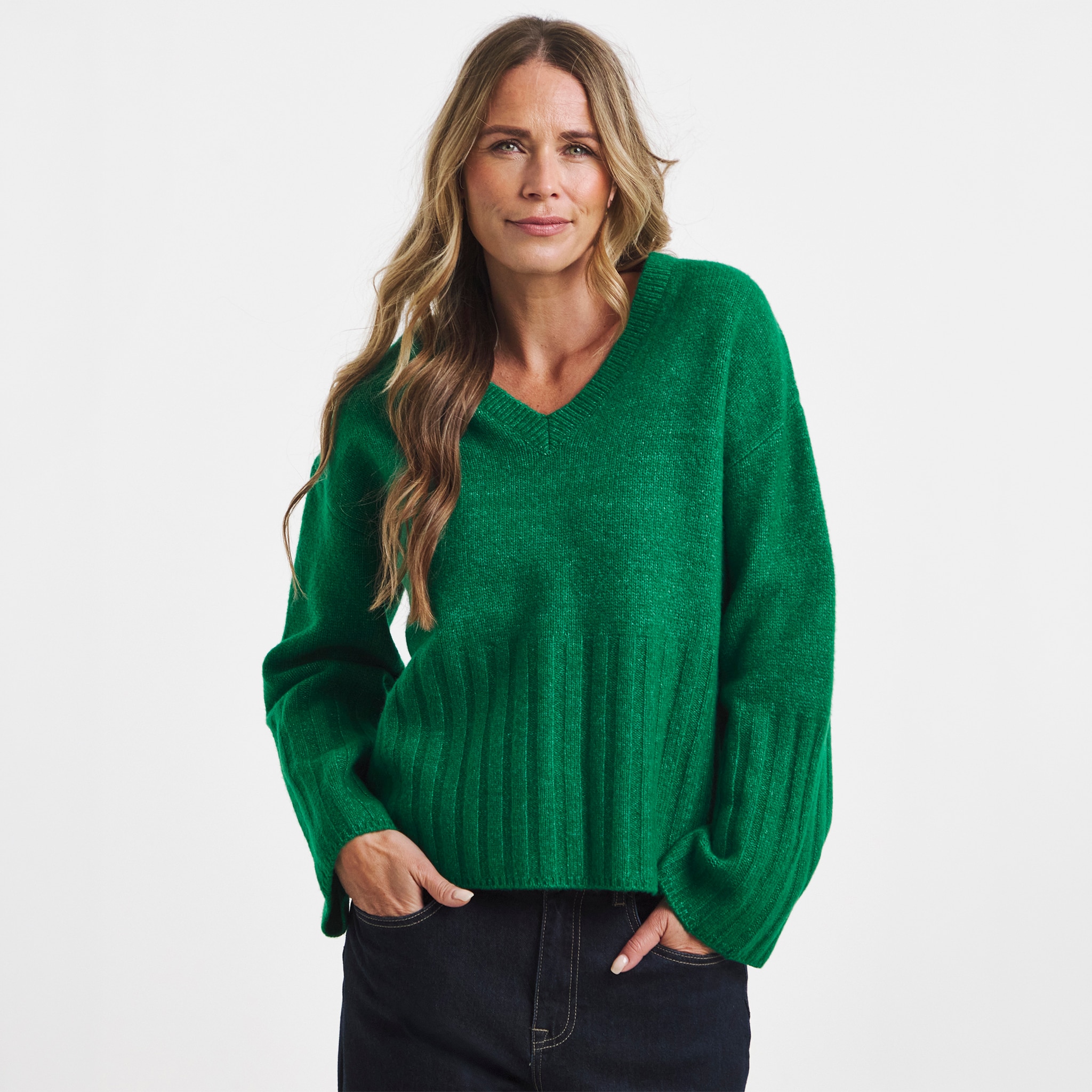 A woman wearing a green v neck jumper.
