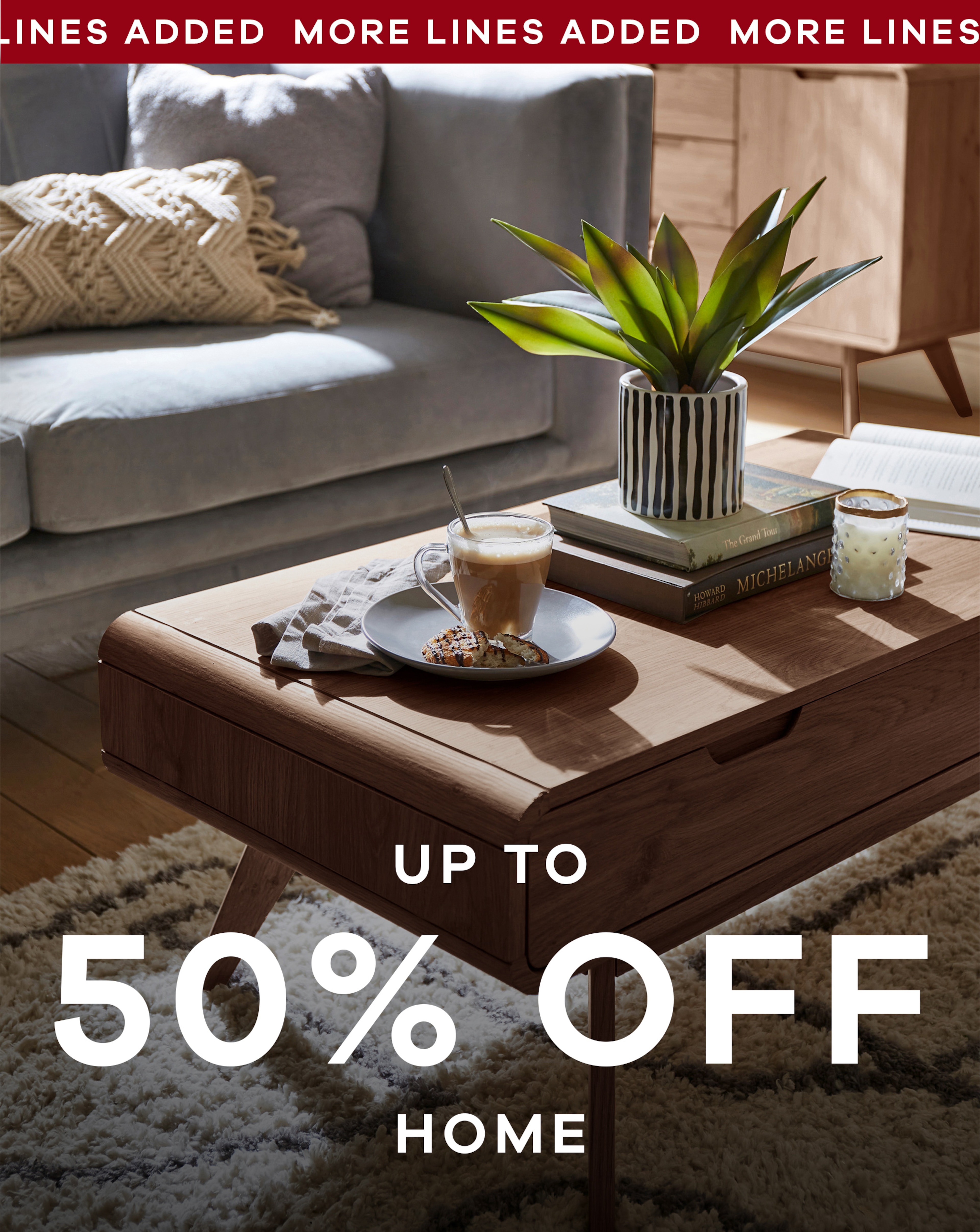 A living room with a coffee table in it with a coffee, cake and a plants on it.