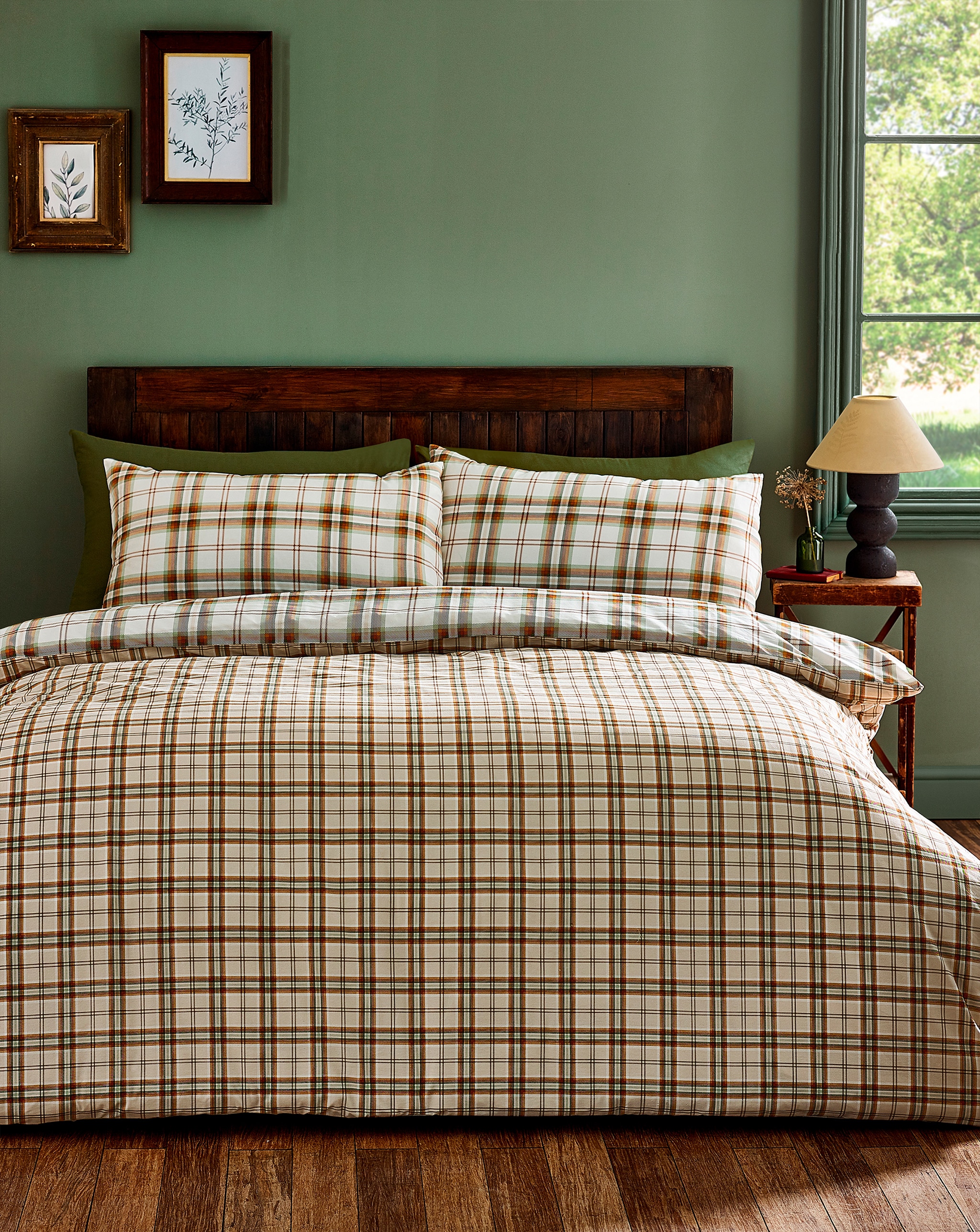A bedroom with a green wall and check brown bedding.