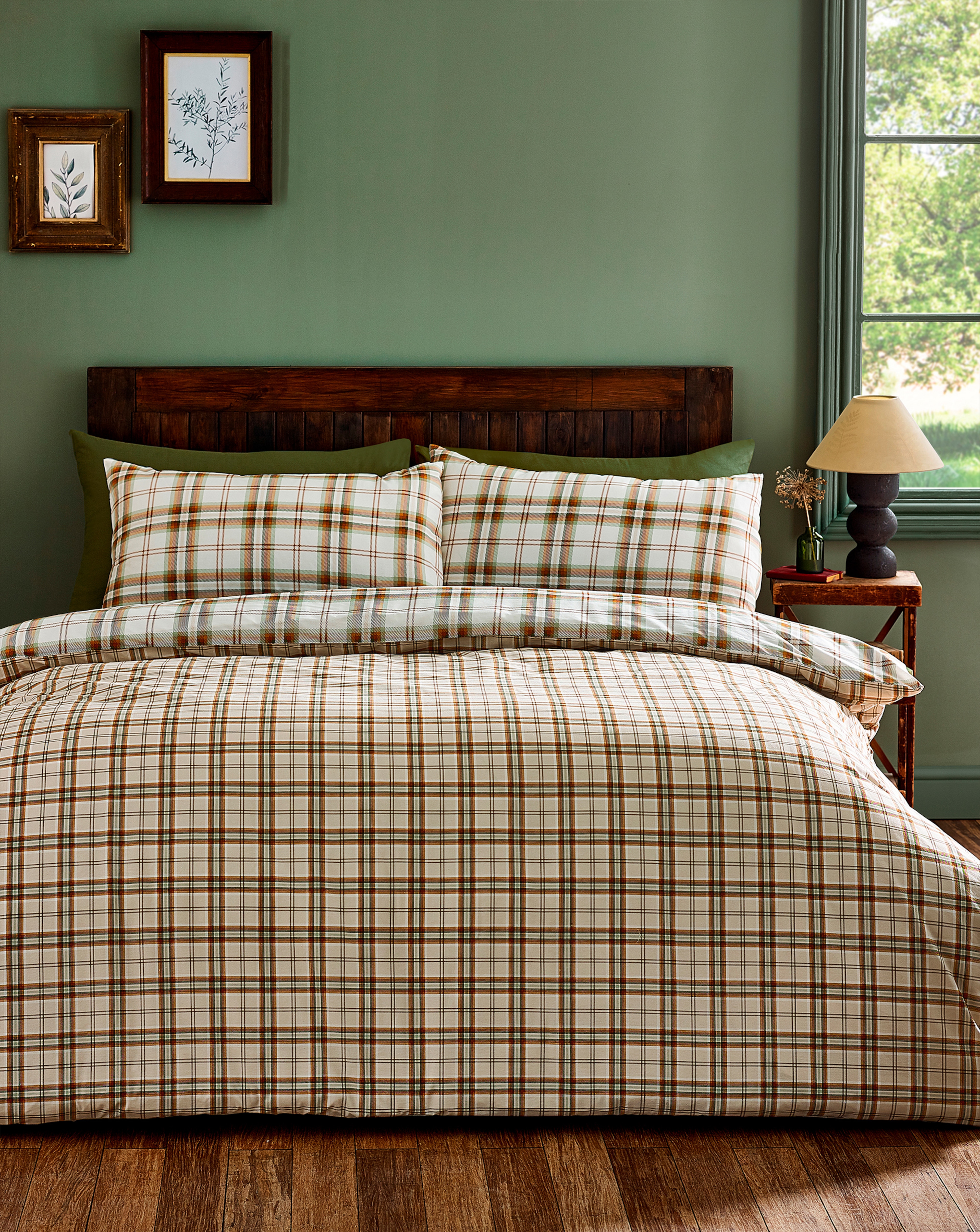 A bedroom with a green wall and check brown bedding.