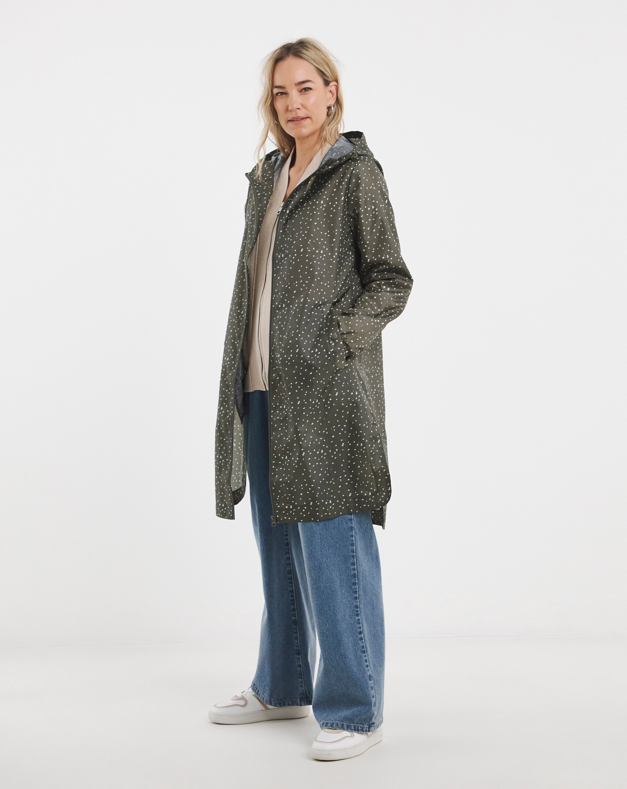 A woman wearing a green with white spot ligtweight coat.