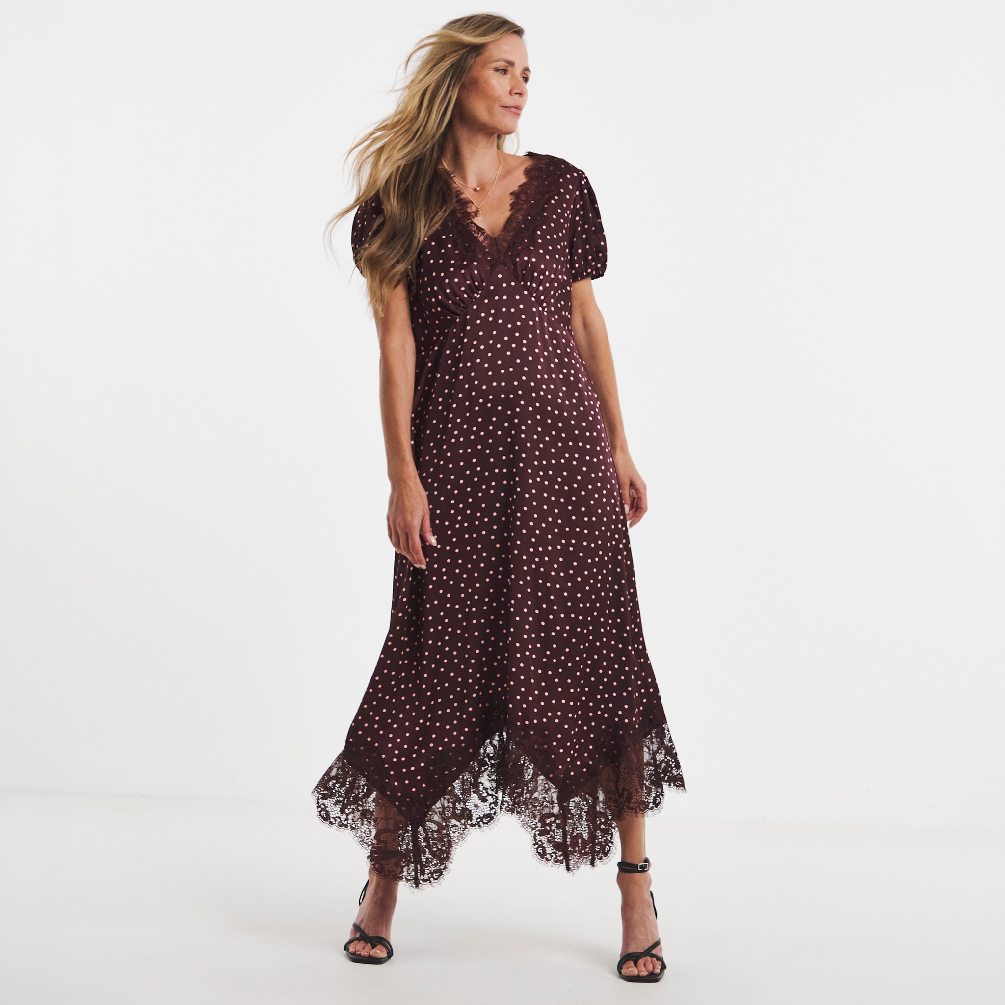 A woman stood wearing a burgundy dress with white spots on it.