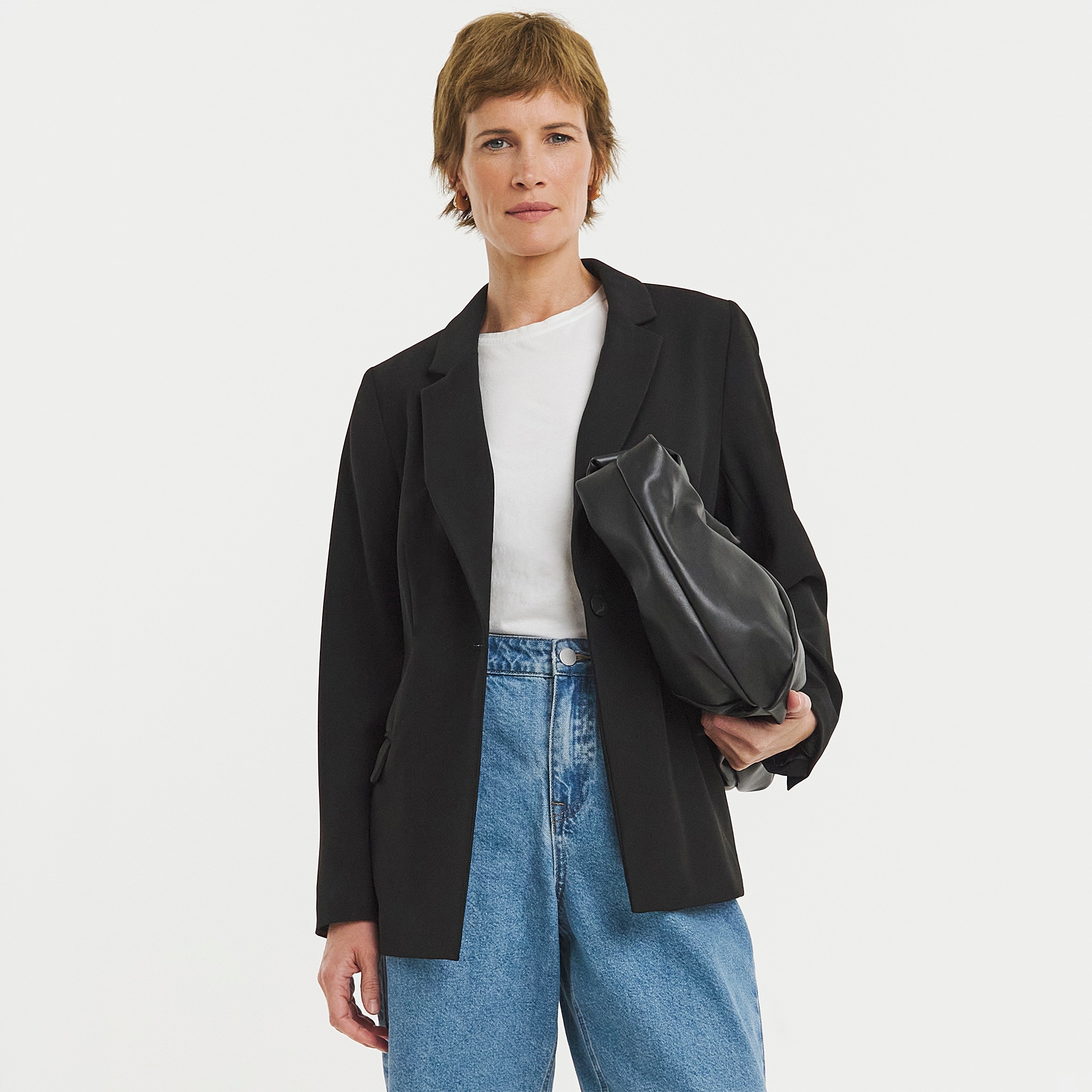 A woman stood wearing a black blazer and blue jeans.