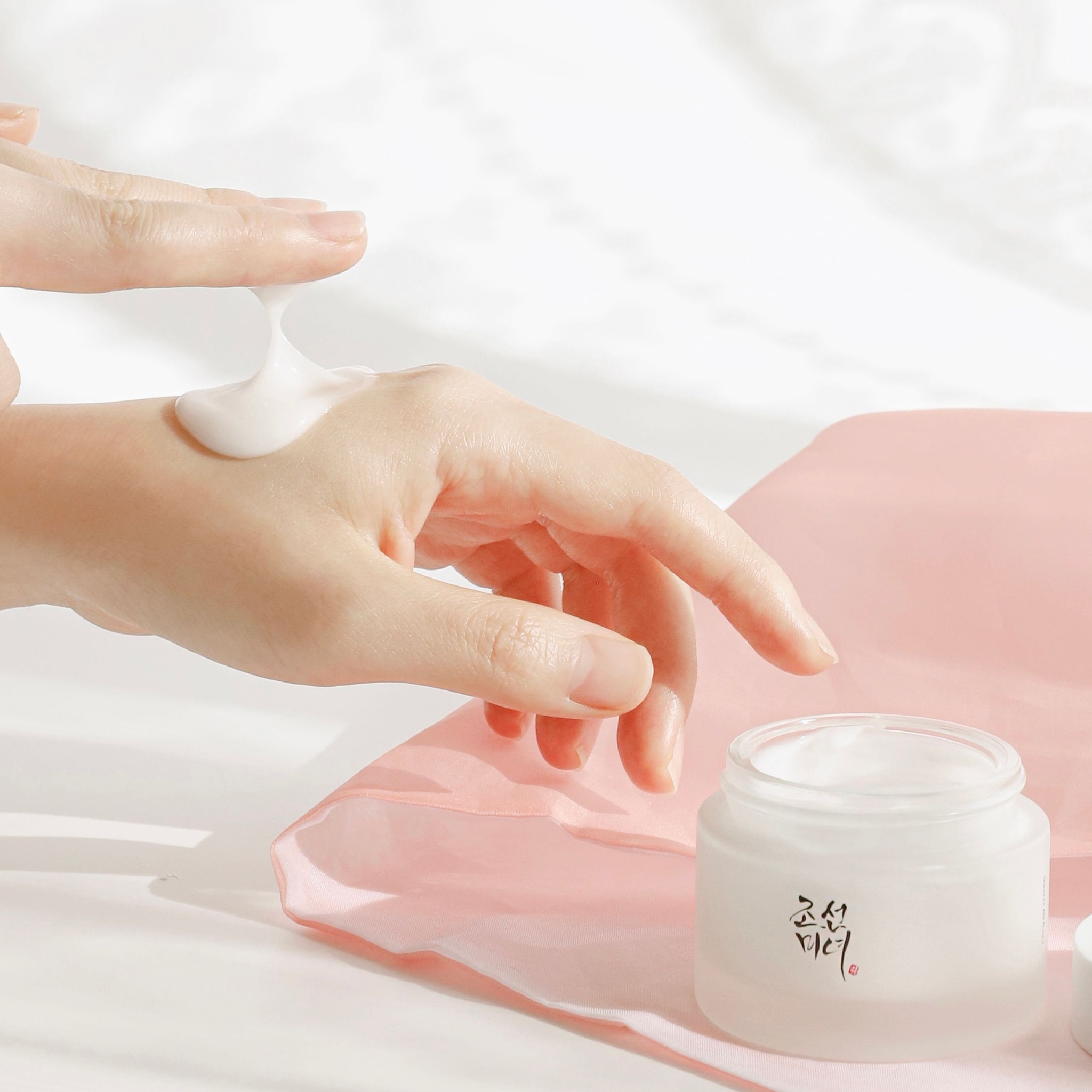 Close-up of a person applying Beauty of Joseon Dynasty Cream skincare cream to the back of their hand.
