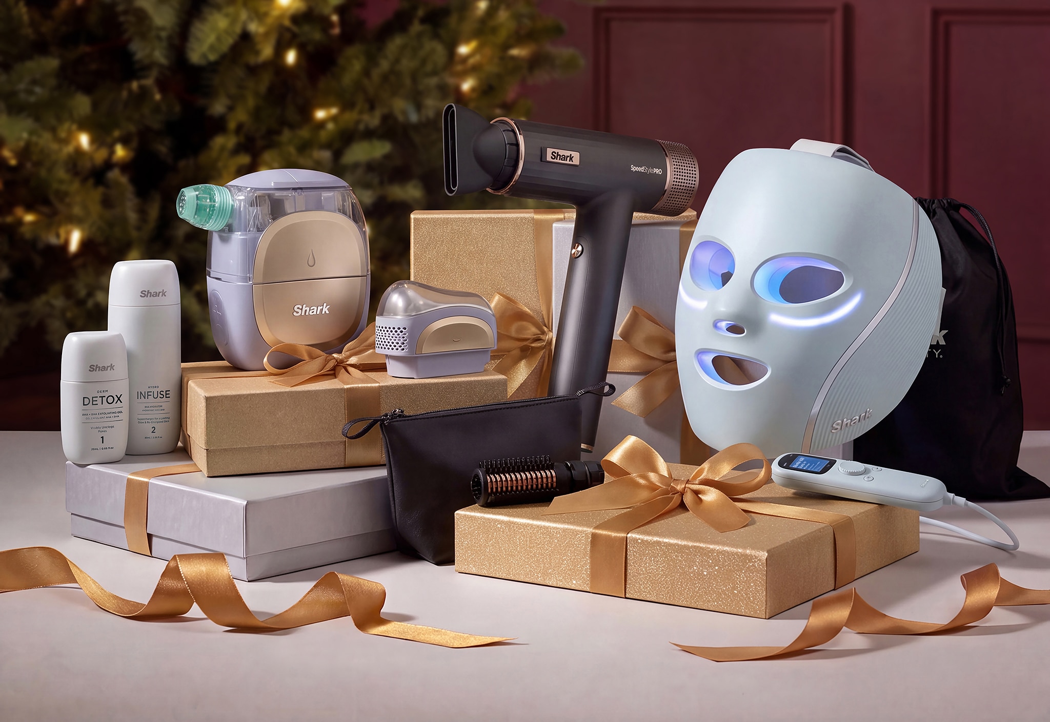 A collection of Shark electrical beauty products on a table surrounded by gift boxes and gold ribbons.