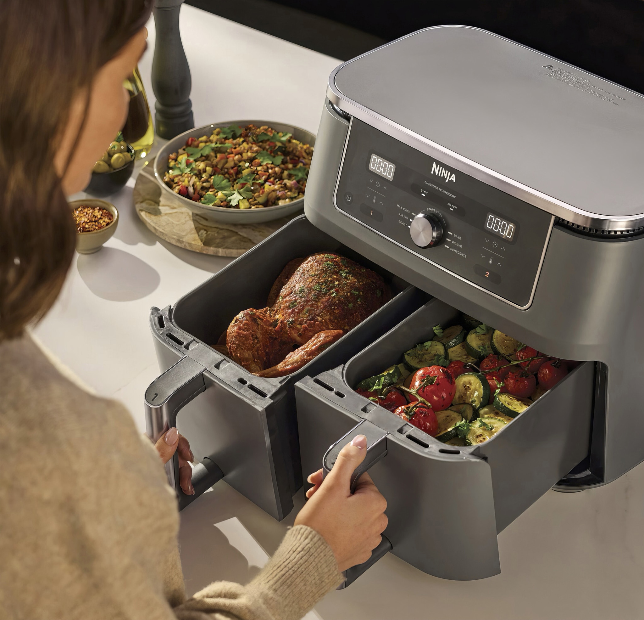 A woman using a Ninja dual drawer air fryer.
