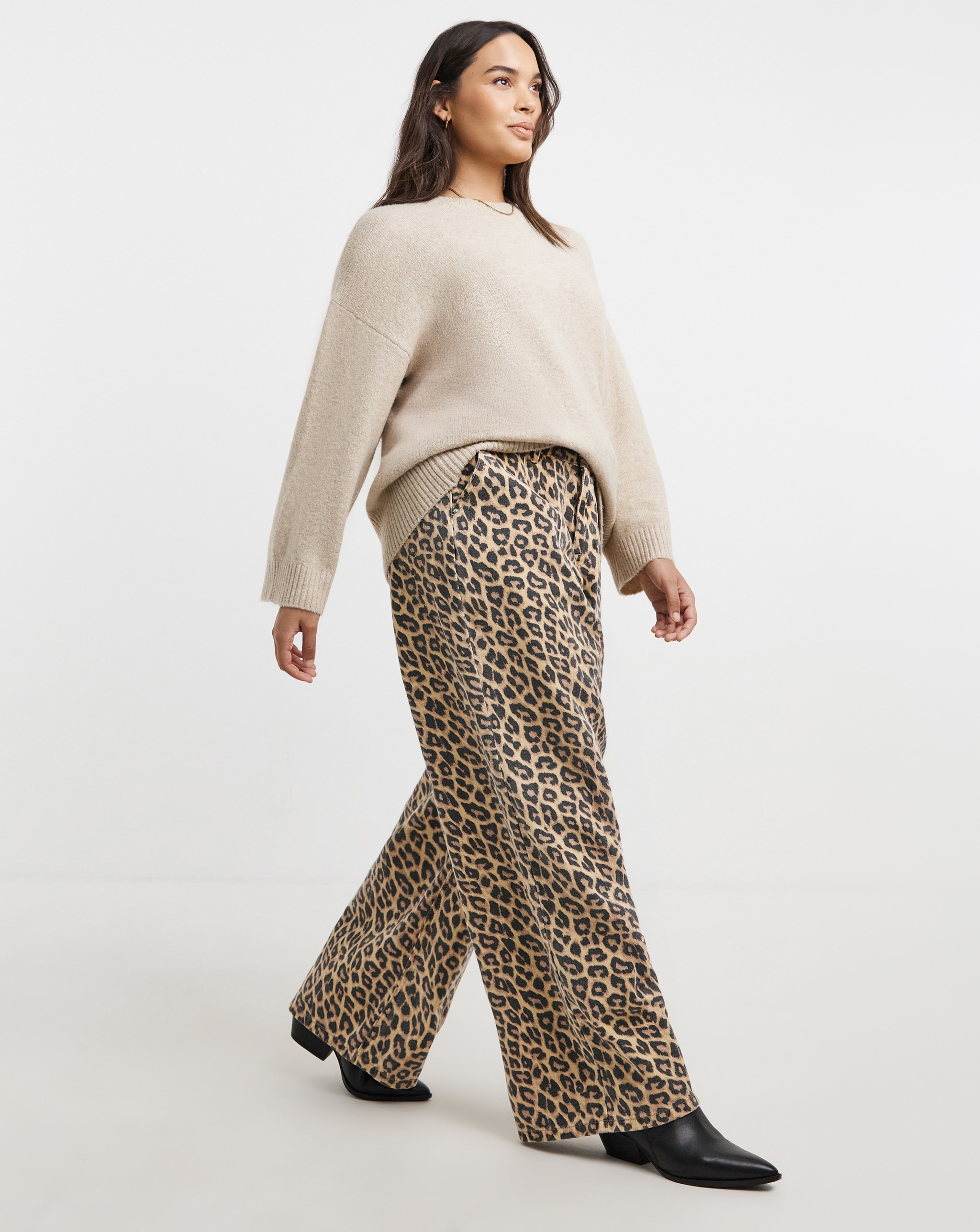 Person wearing a beige jumper with leopard-print wide-leg trousers and black boots.