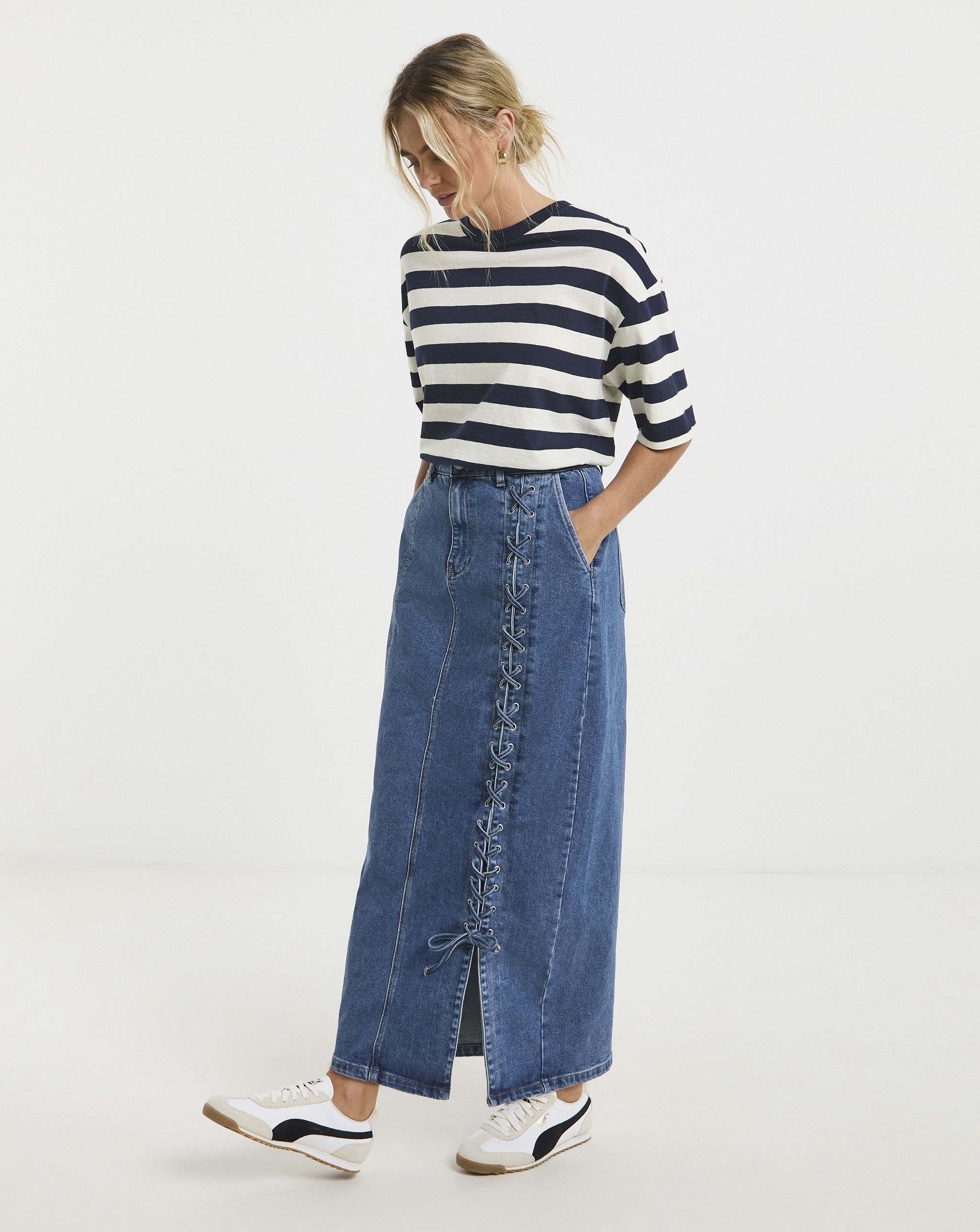 A lady wearing a white and blue hooped top with a denim maxi skirt.