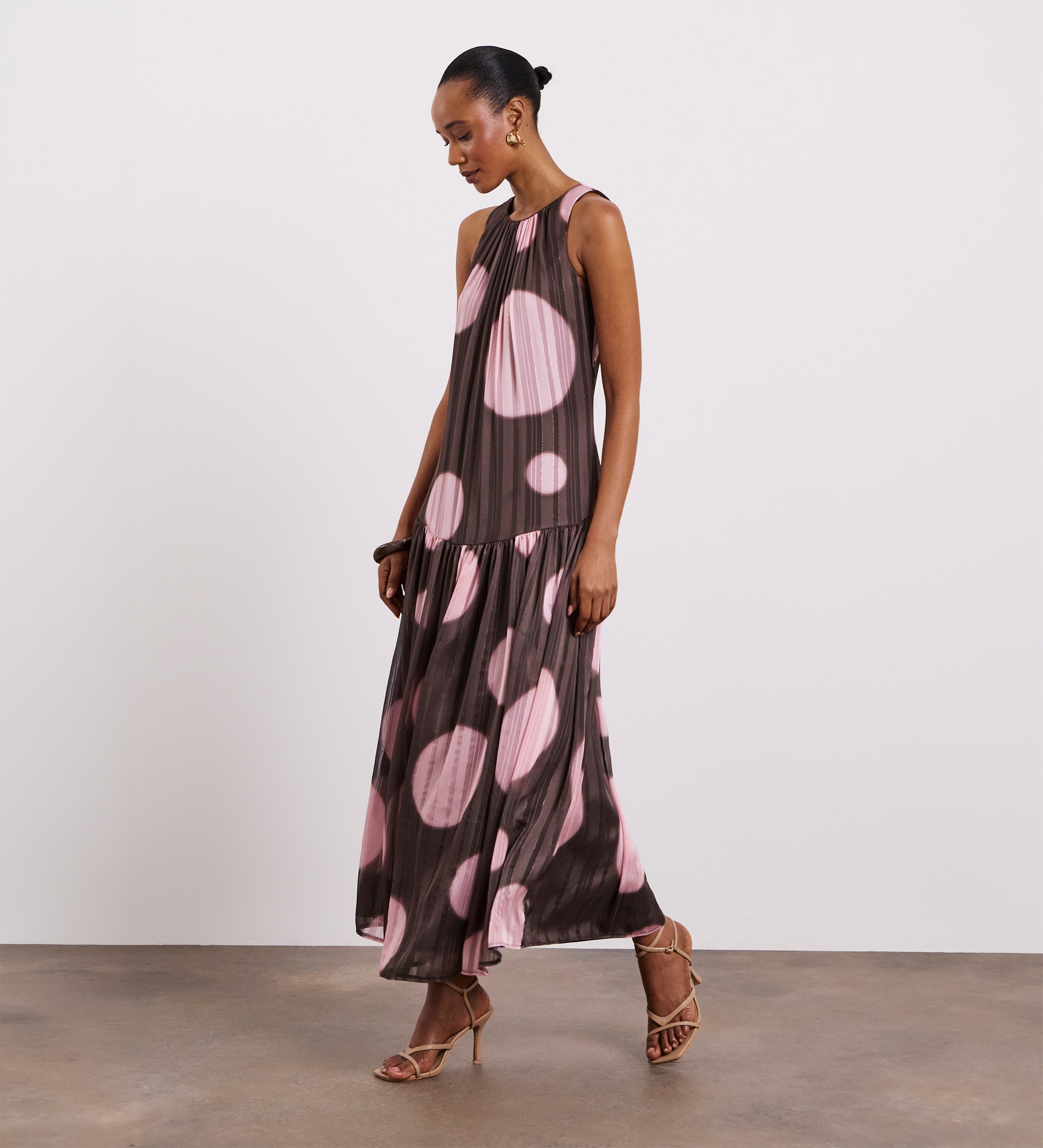 A woman wearing a brown with pink circles pleated dress.