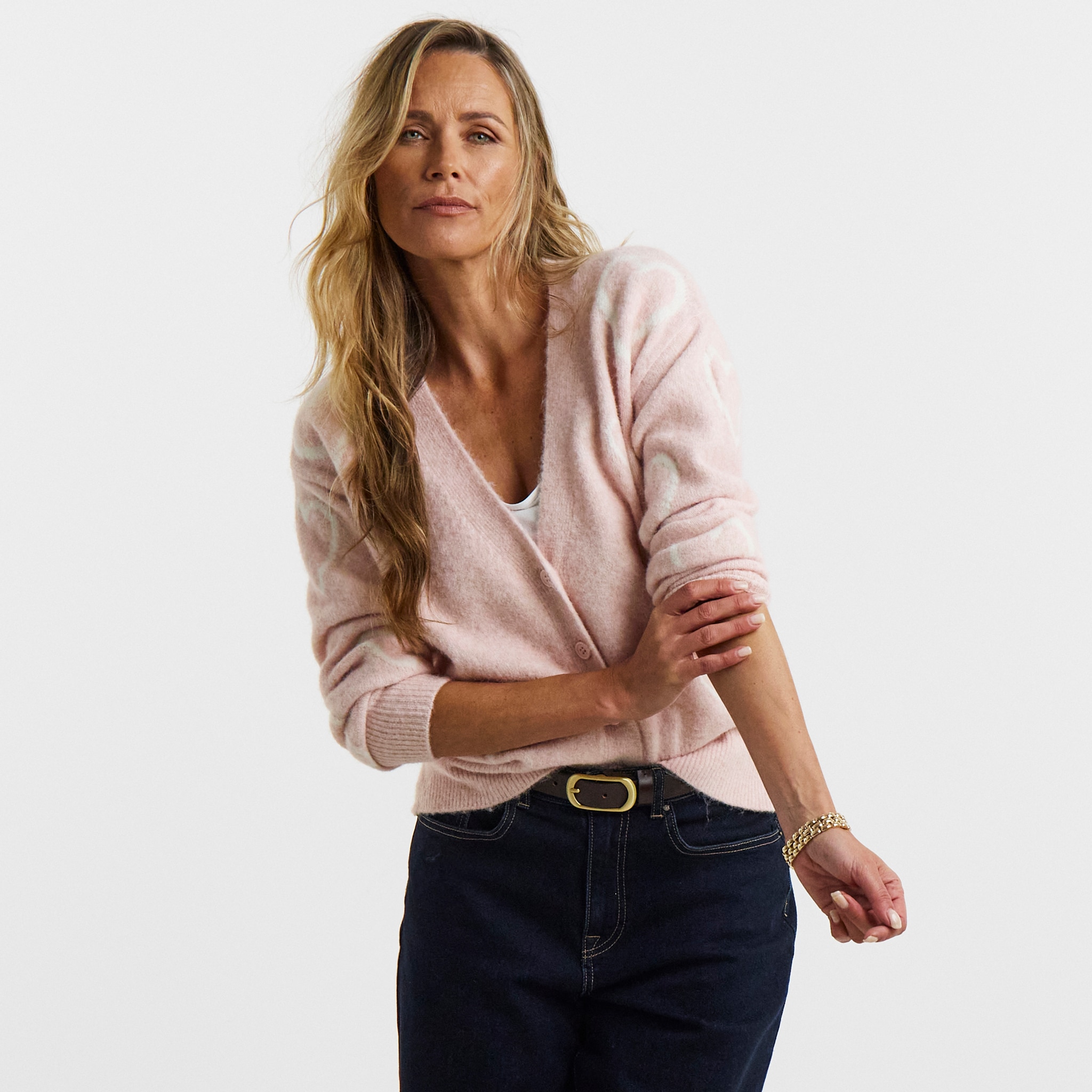 A woman wearing a pink button up cardigan.