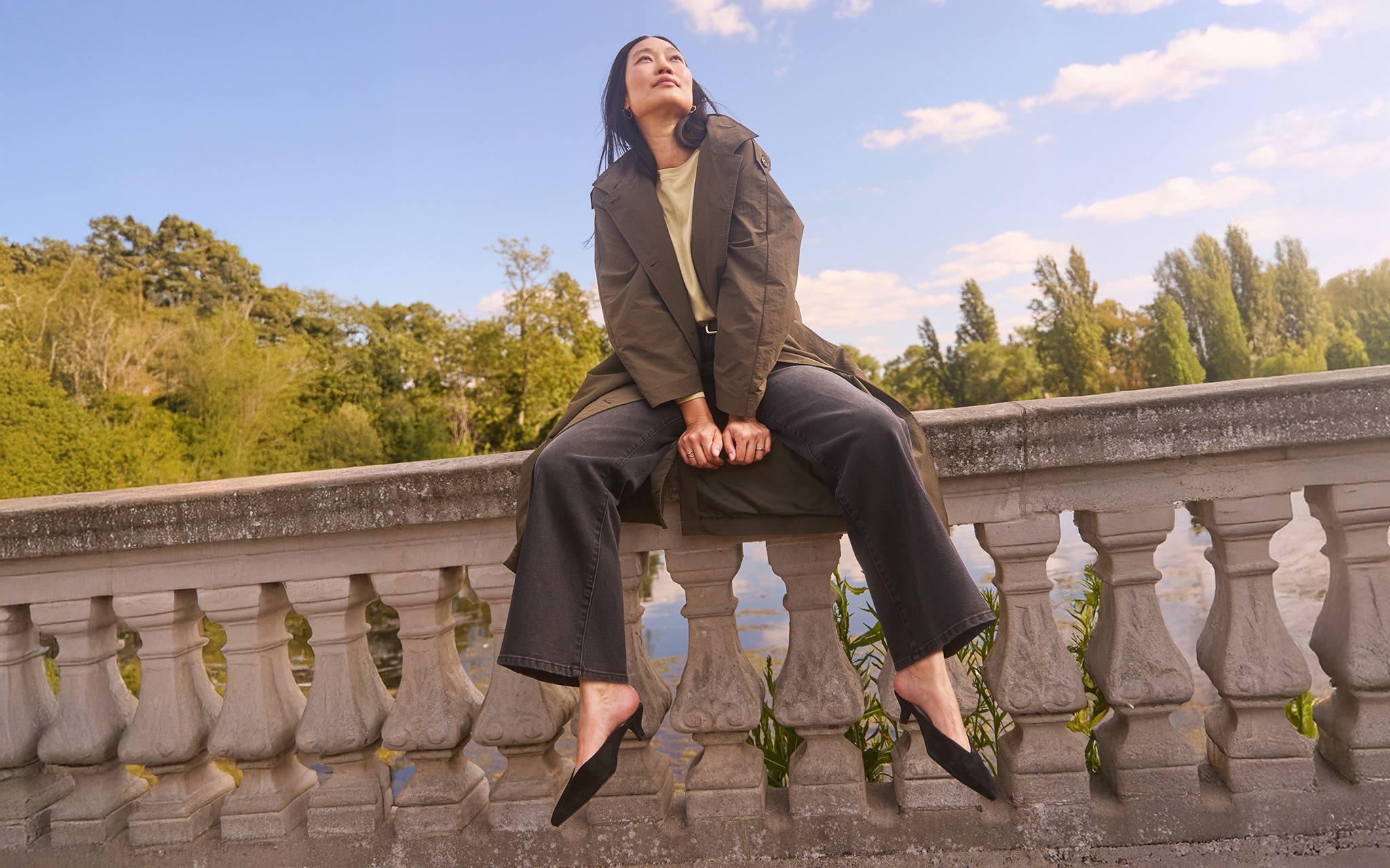 A lady sat on a wall wearing black wide leg trousers.