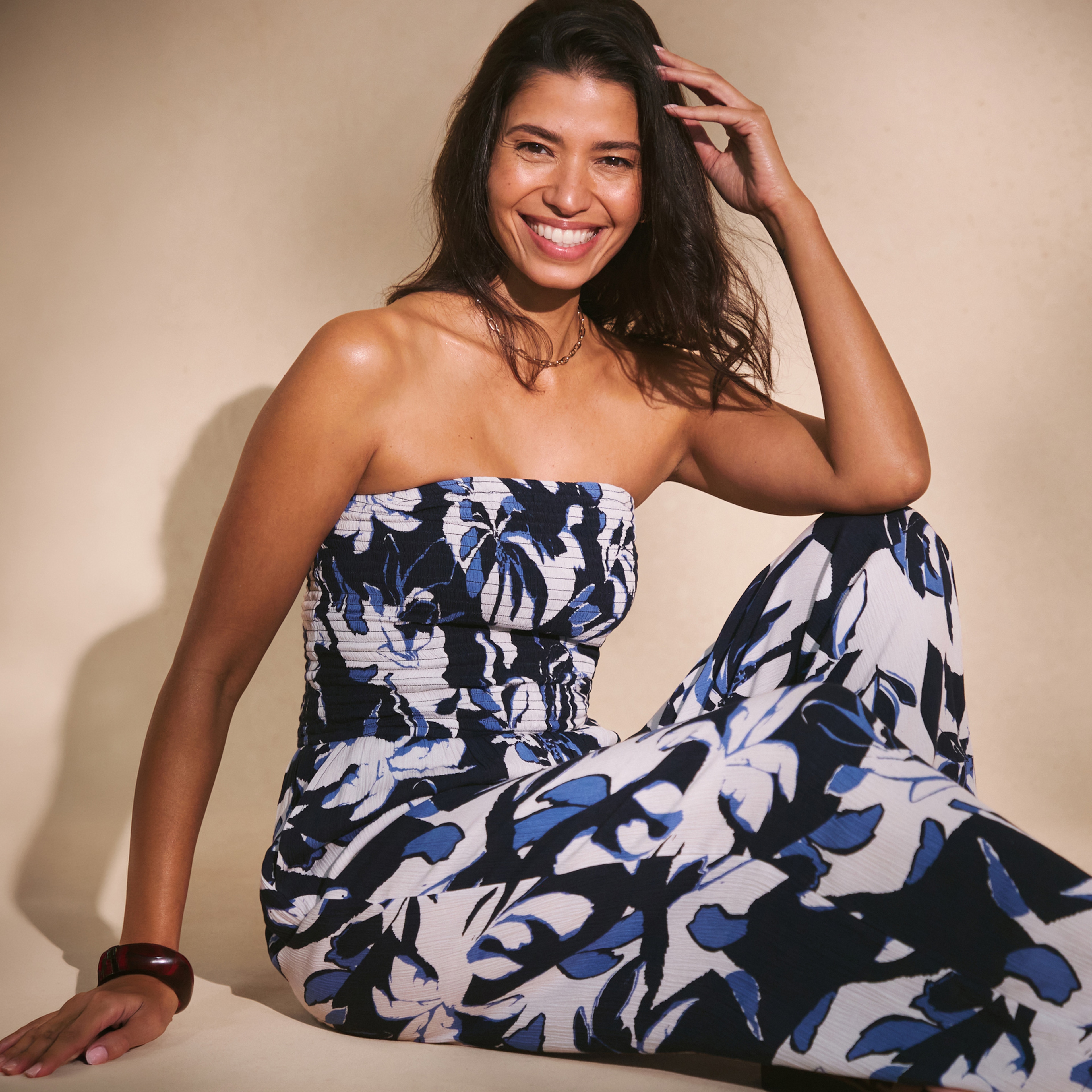 A lady sat on the floor wearing a blue black and white printed dress.