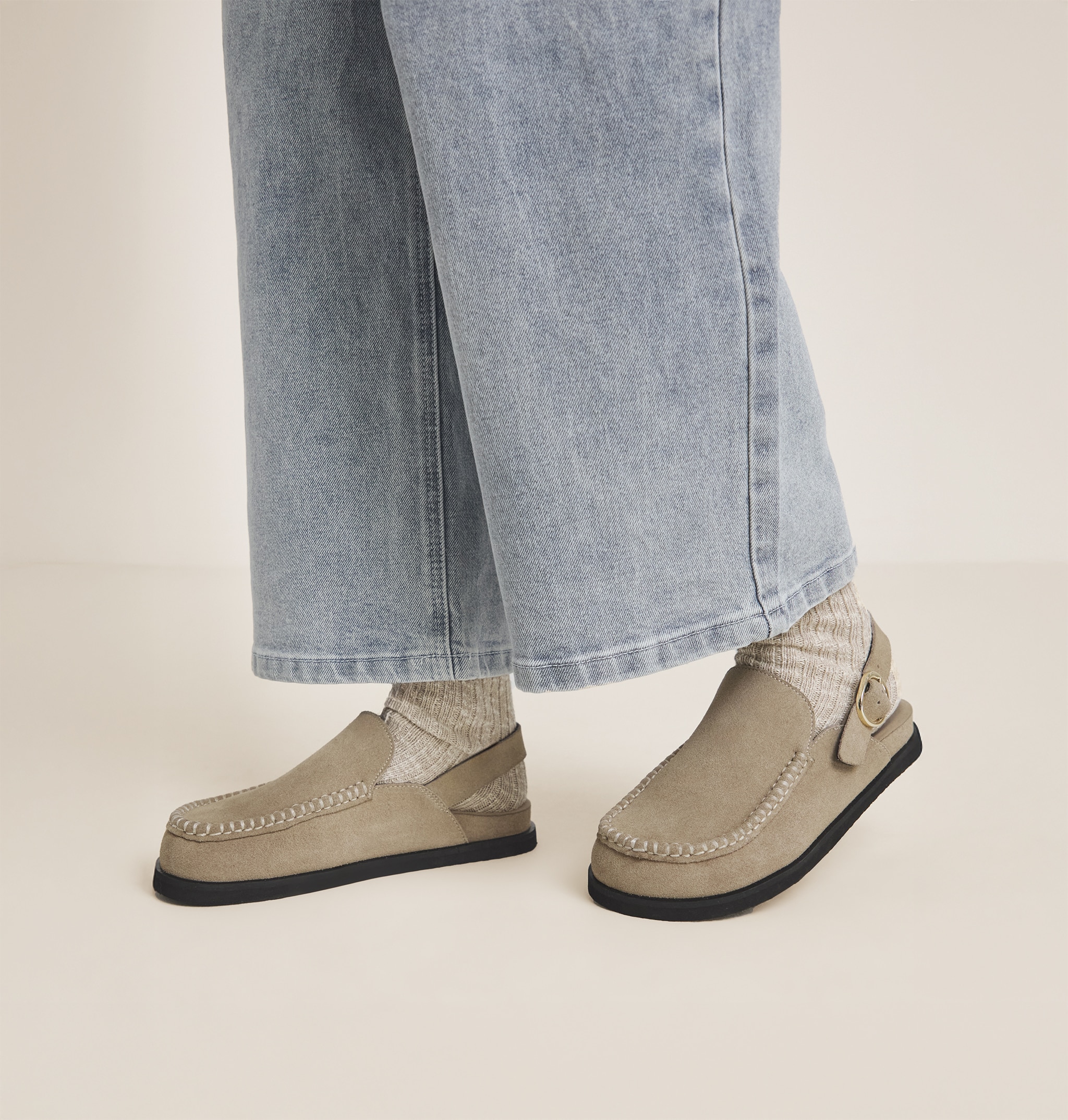 A person wearing sand coloured Mules footwear