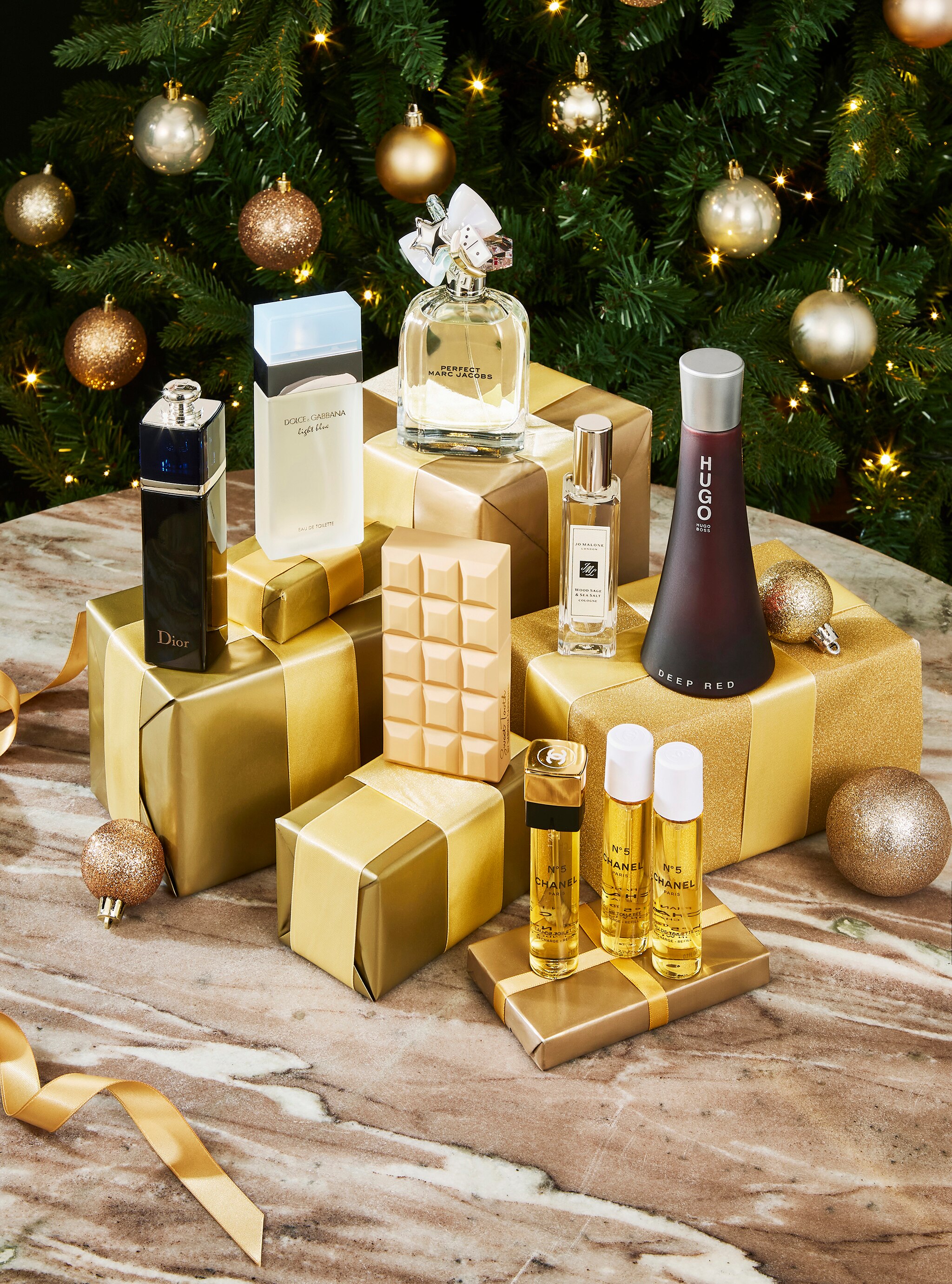 A range of beauty gifts on a table with a Christmas tree in the background.