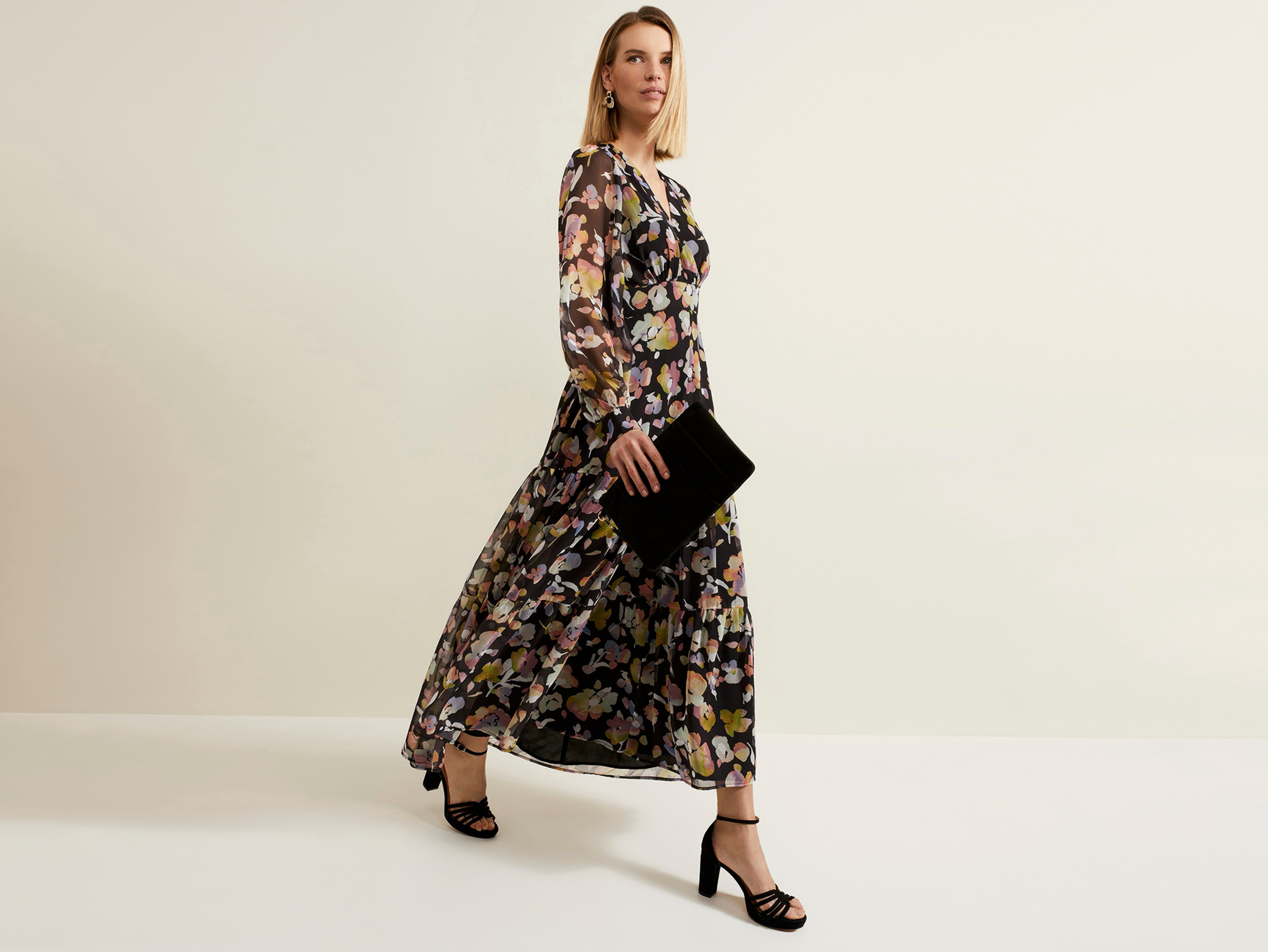 Woman walking wearing a black and bronze patterned maxi dress