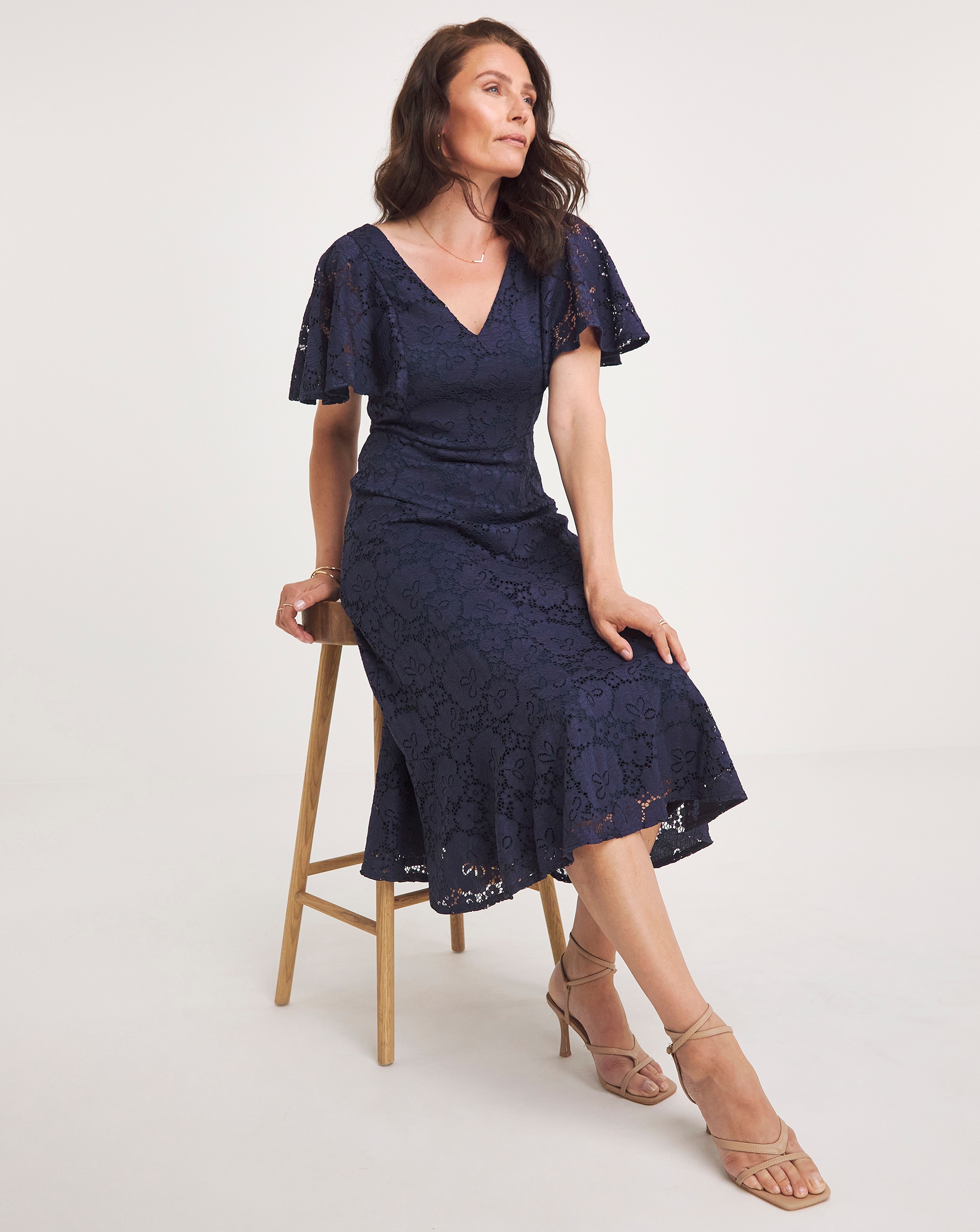 A lady perched on a stool wearing a blue dress.