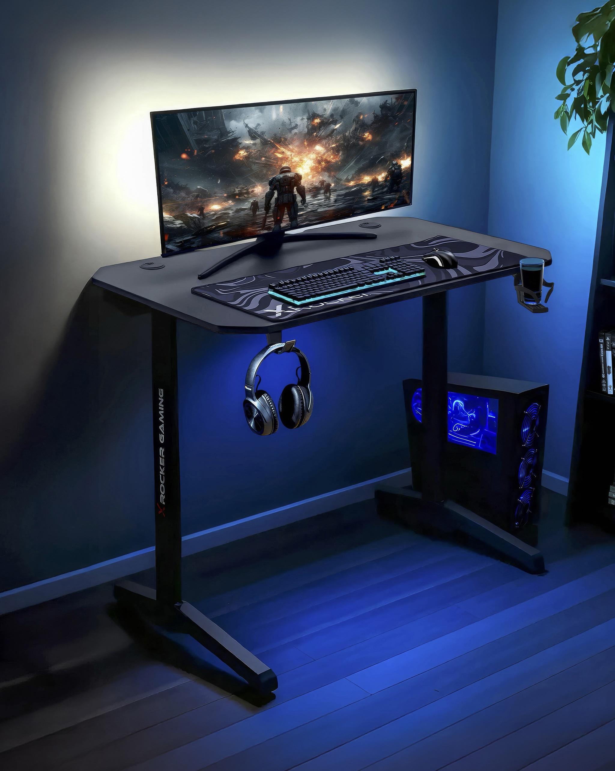 A computer gaming desk with a widescreen monitor, keyboard, mouse, headphone and computer tower on the floor. A blue backlight on the desk.