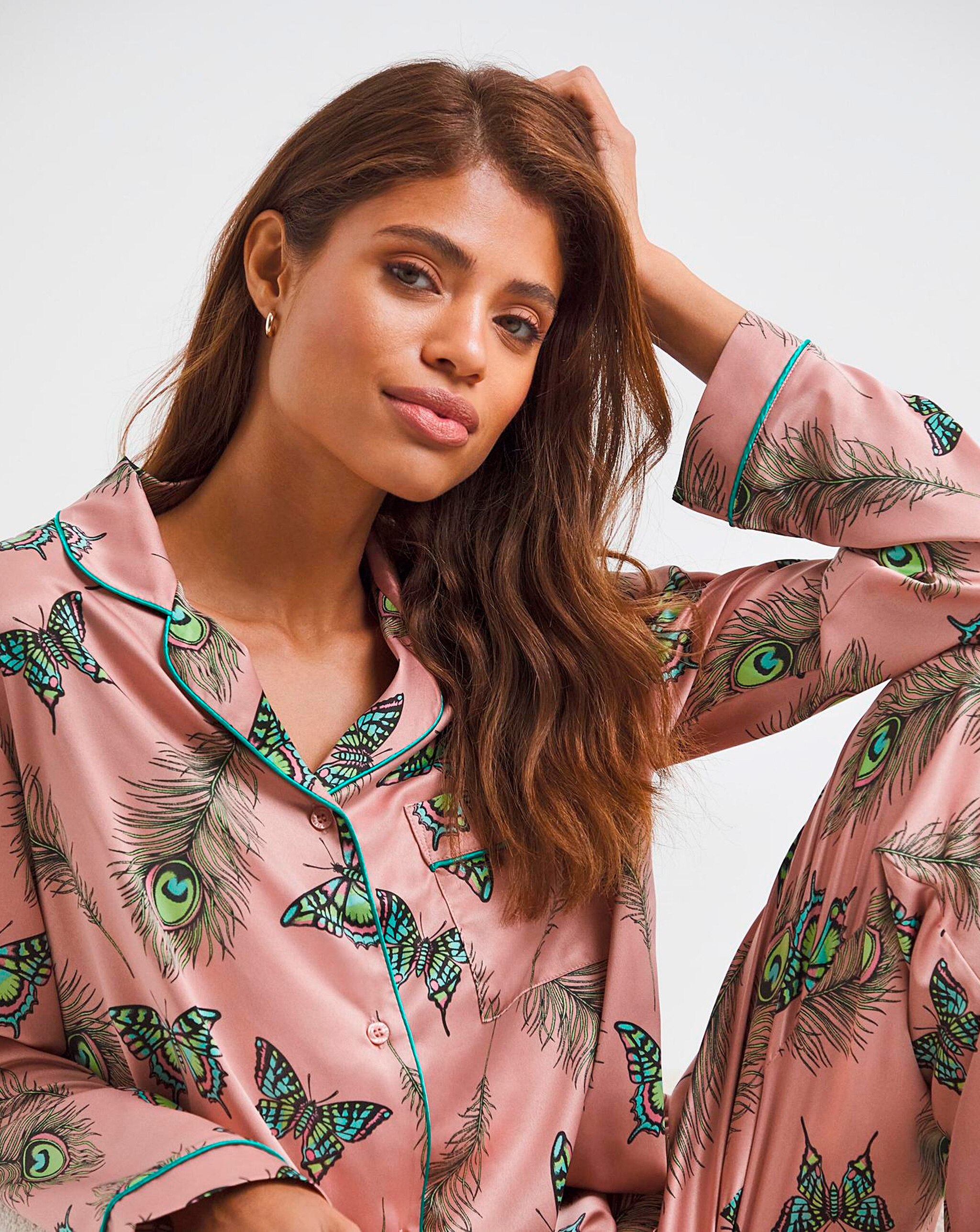 Model wearing pink pyjamas with  peacock and butterfly print