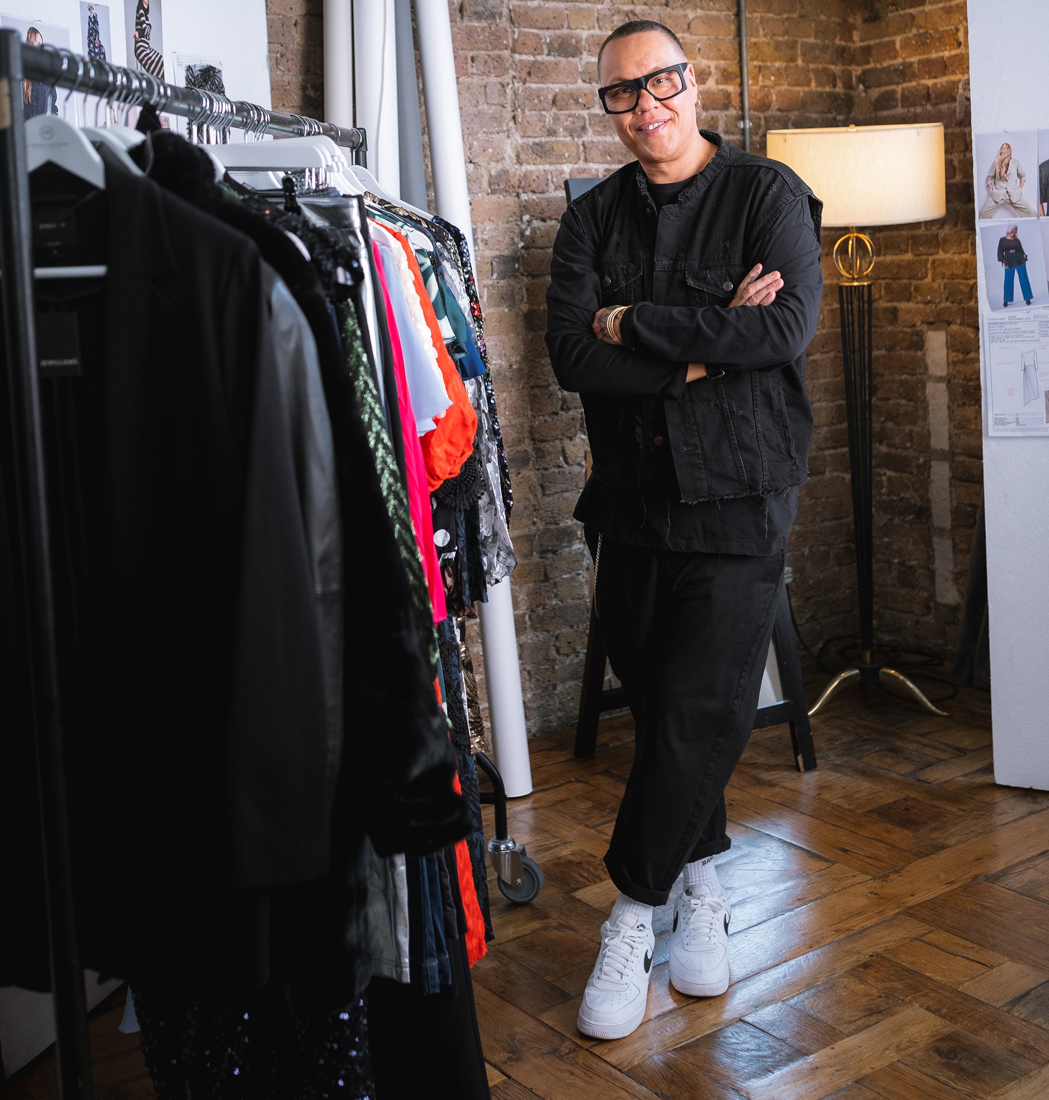 Gok Wan stood next to a rail of clothing.
