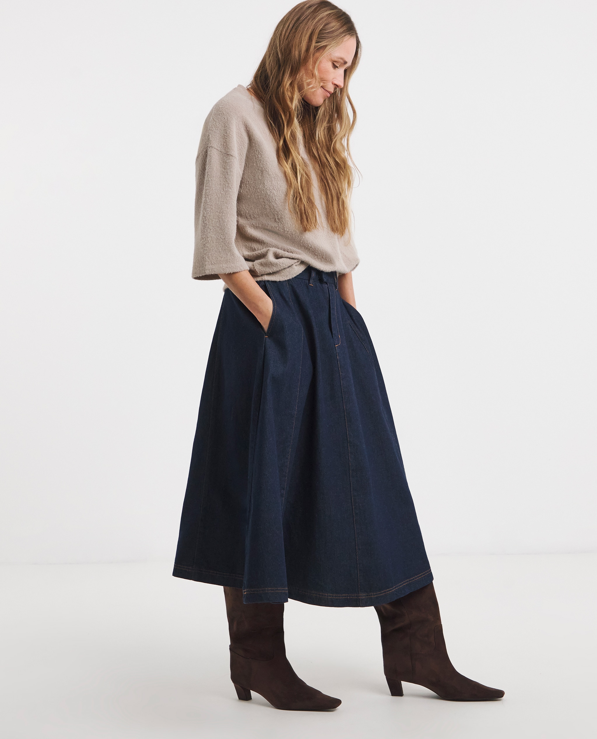 Model is wearing a taupe jumper with a indigo seamed full circle midi skirt and chocolate boots.