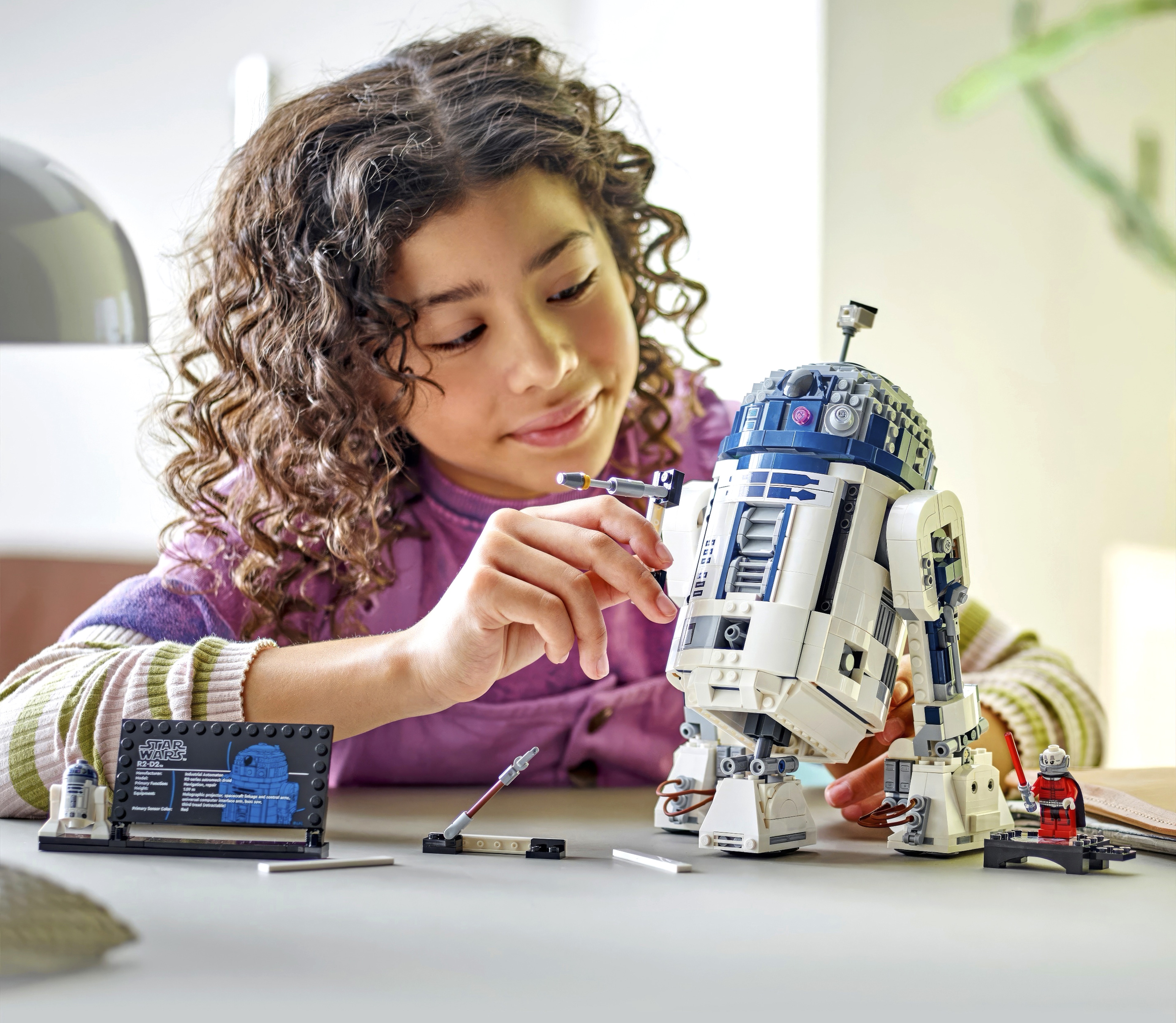 A child playing with a LEGO® Star Wars™ R2-D2 play set.