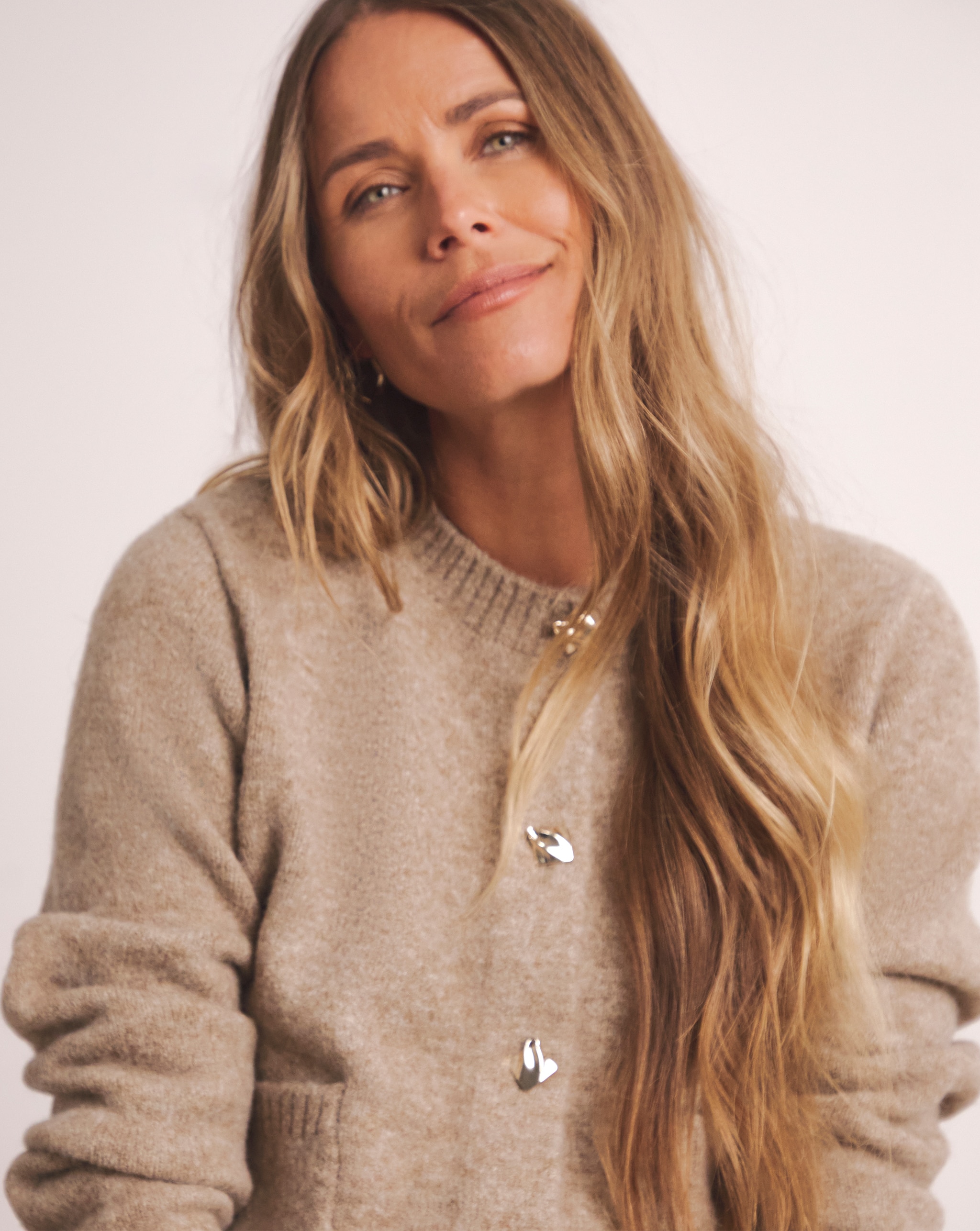 Person wearing a soft, beige button-up cardigan with metallic buttons.