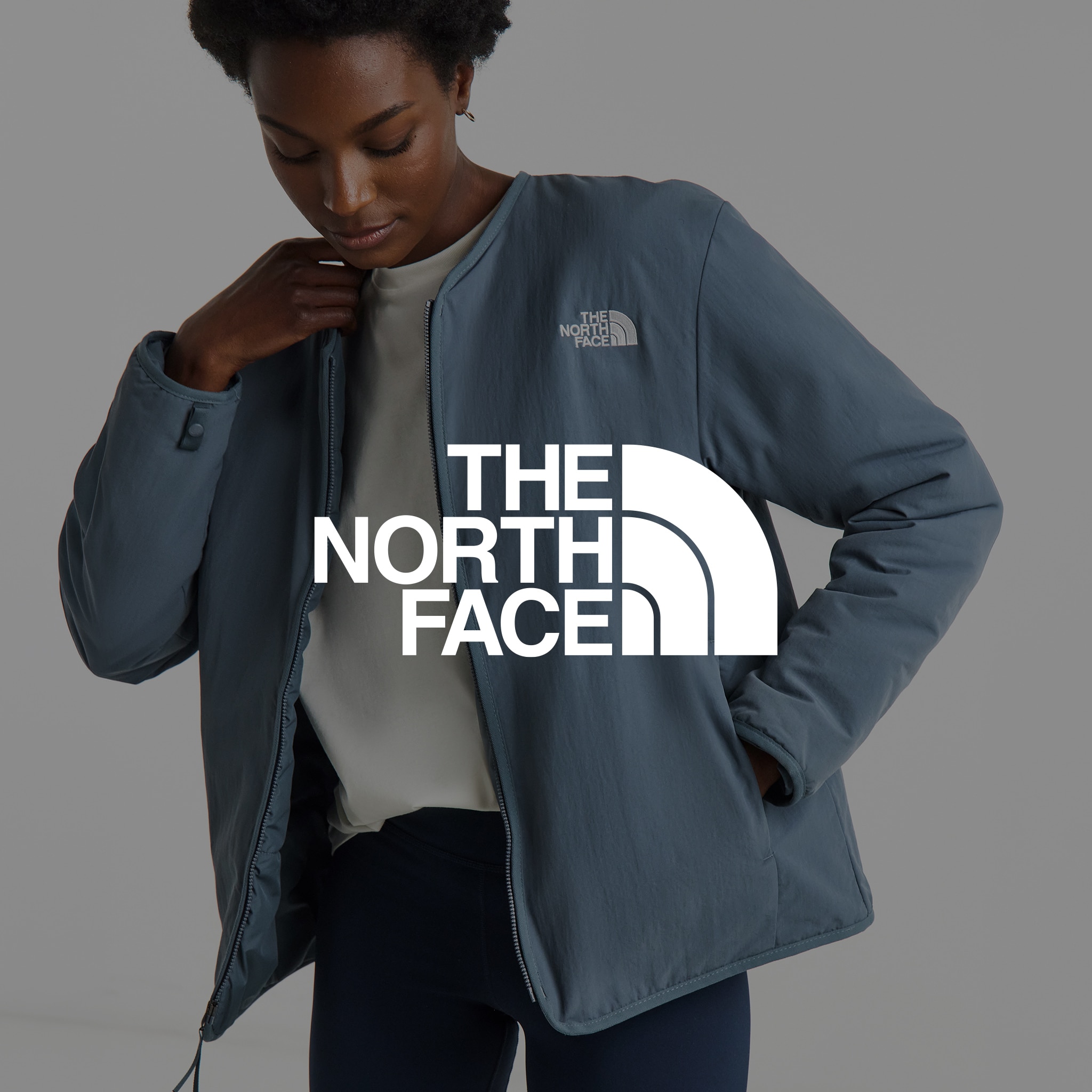 A lady wearing a North Face blue jacket. The North Face logo is overlaid on the image.