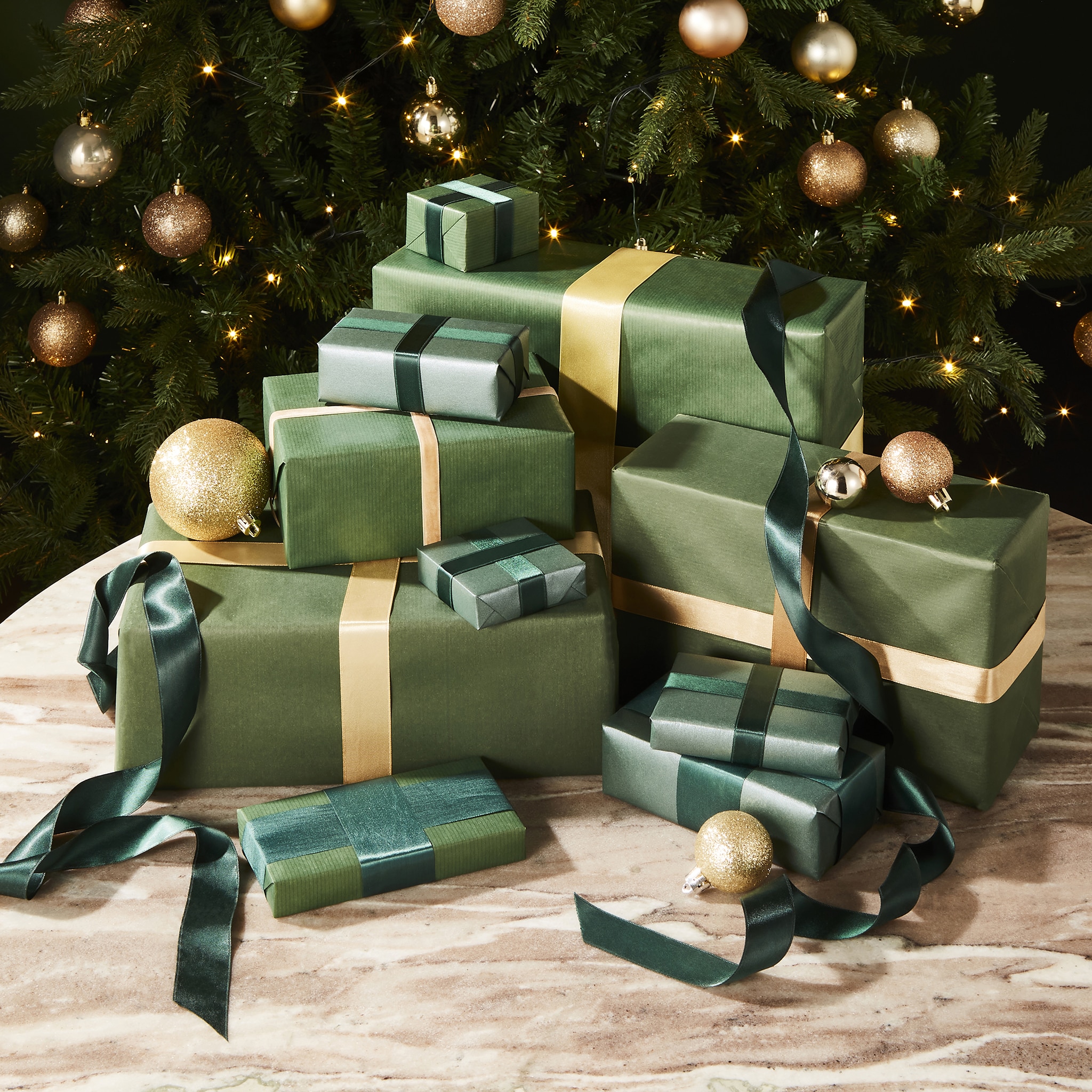 A pile of green presents wrapped up with gold ribbons
