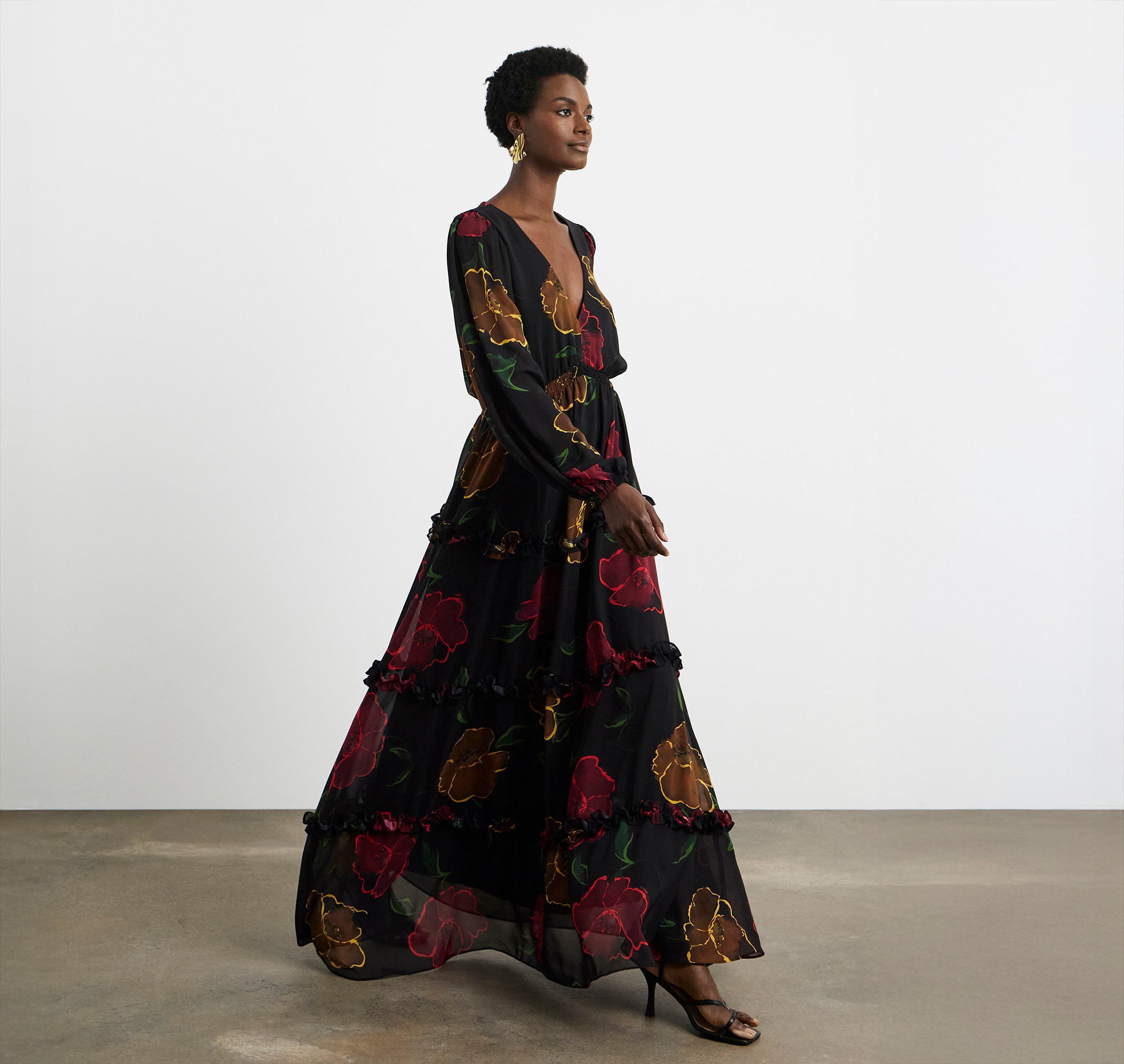 Lady wearing a black dress with red and yellow flowers printed on it.