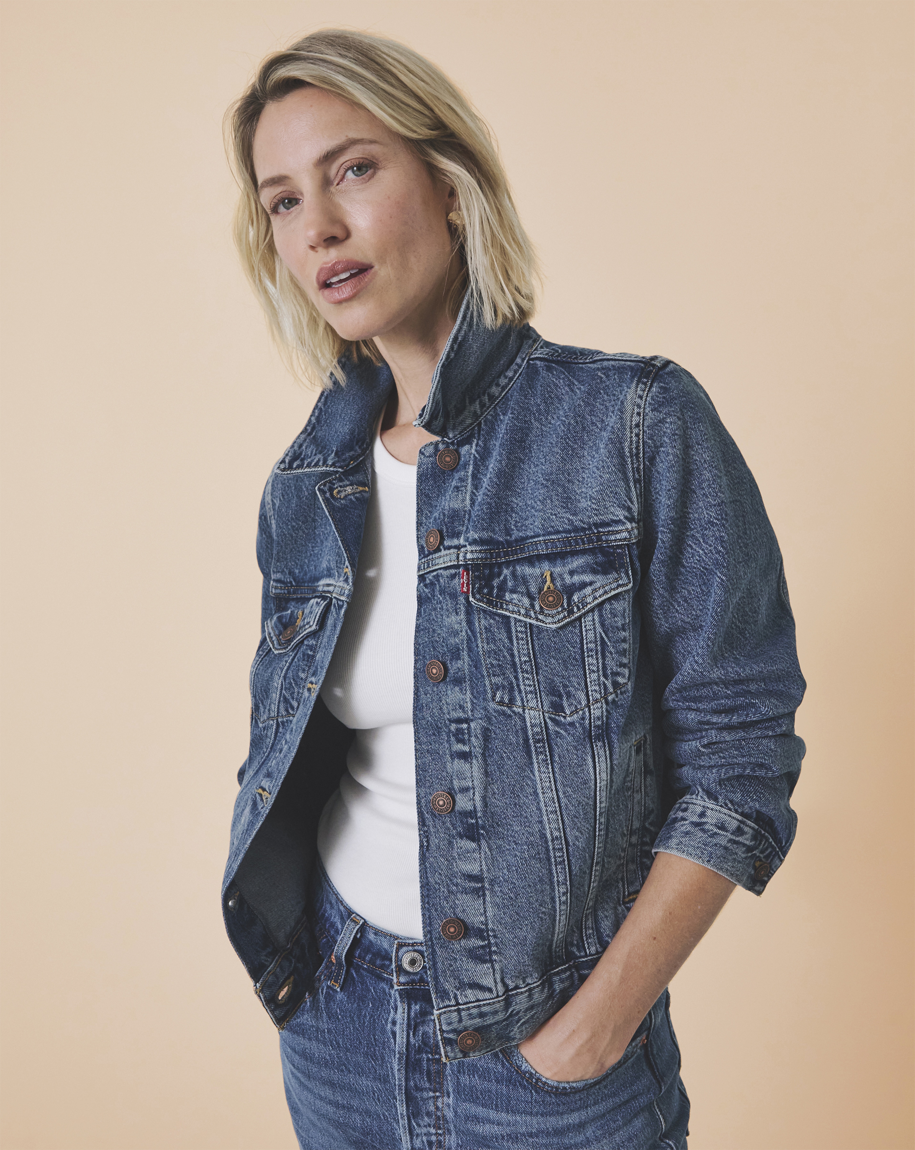 A lady wearing a denim jacket with a white t shirt and jeans.