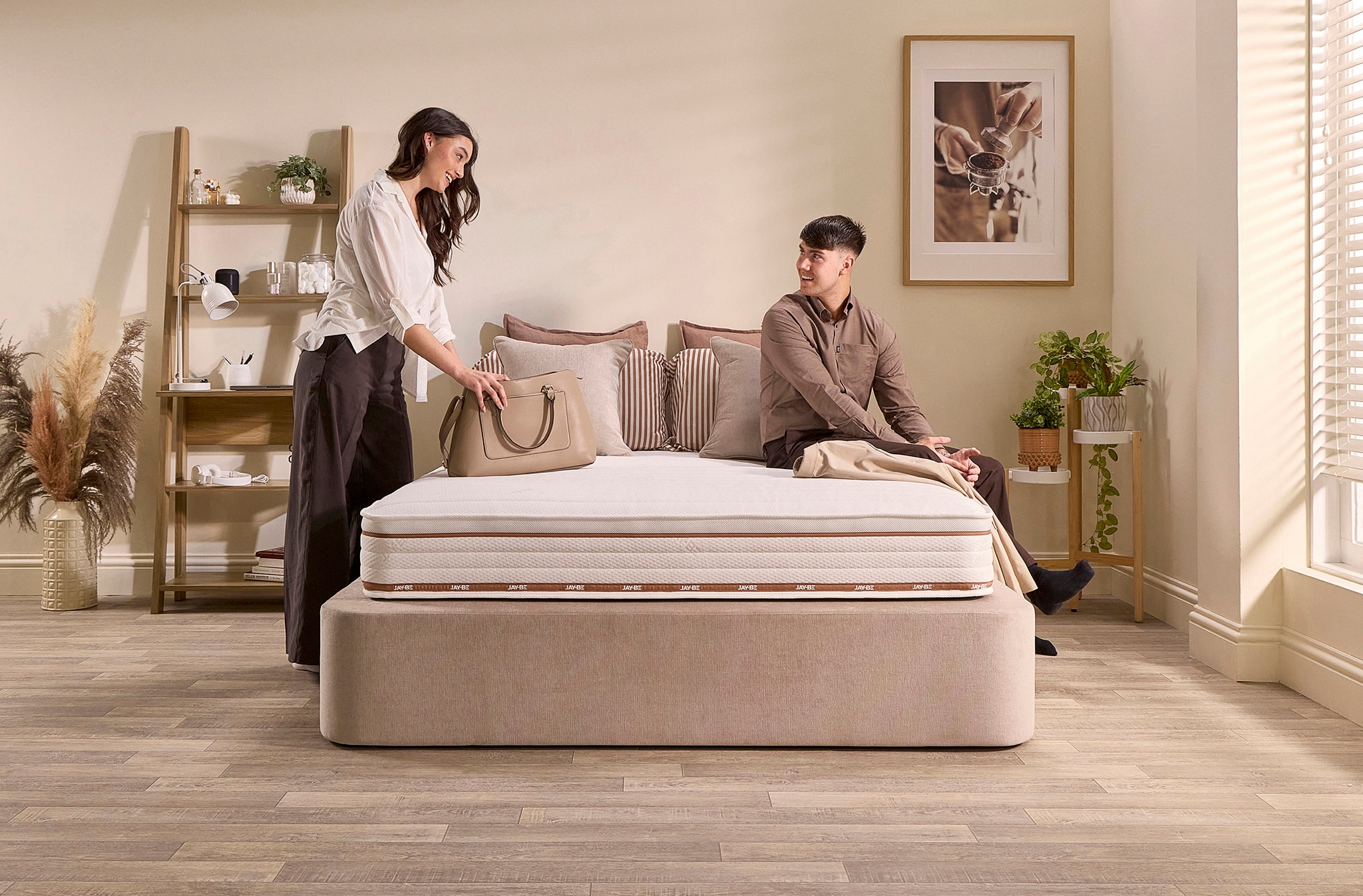 Two people sat and stood next to a mattress