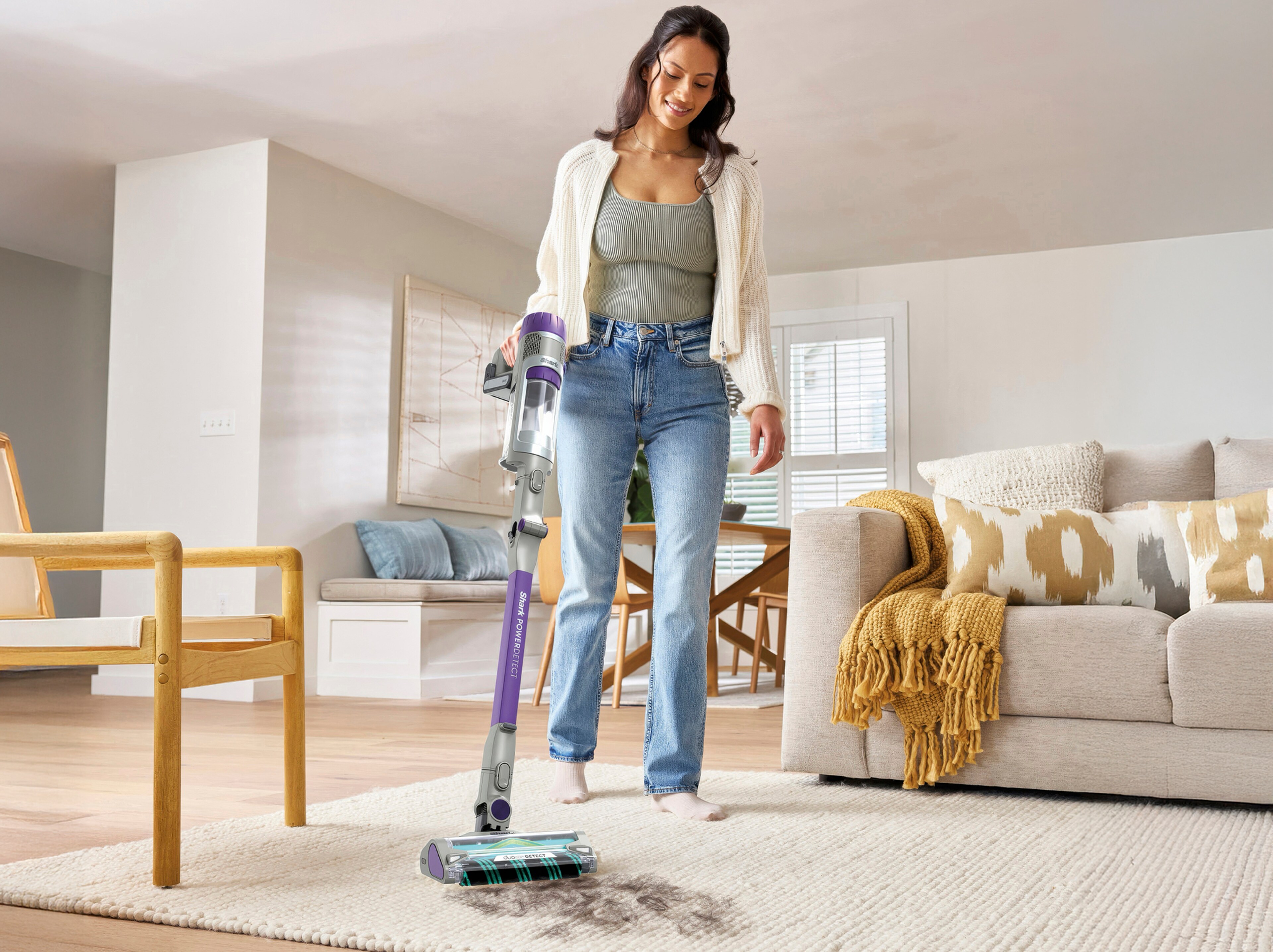 A lady using a Shark cleaning appliance to vacuum up for animal hair / fur