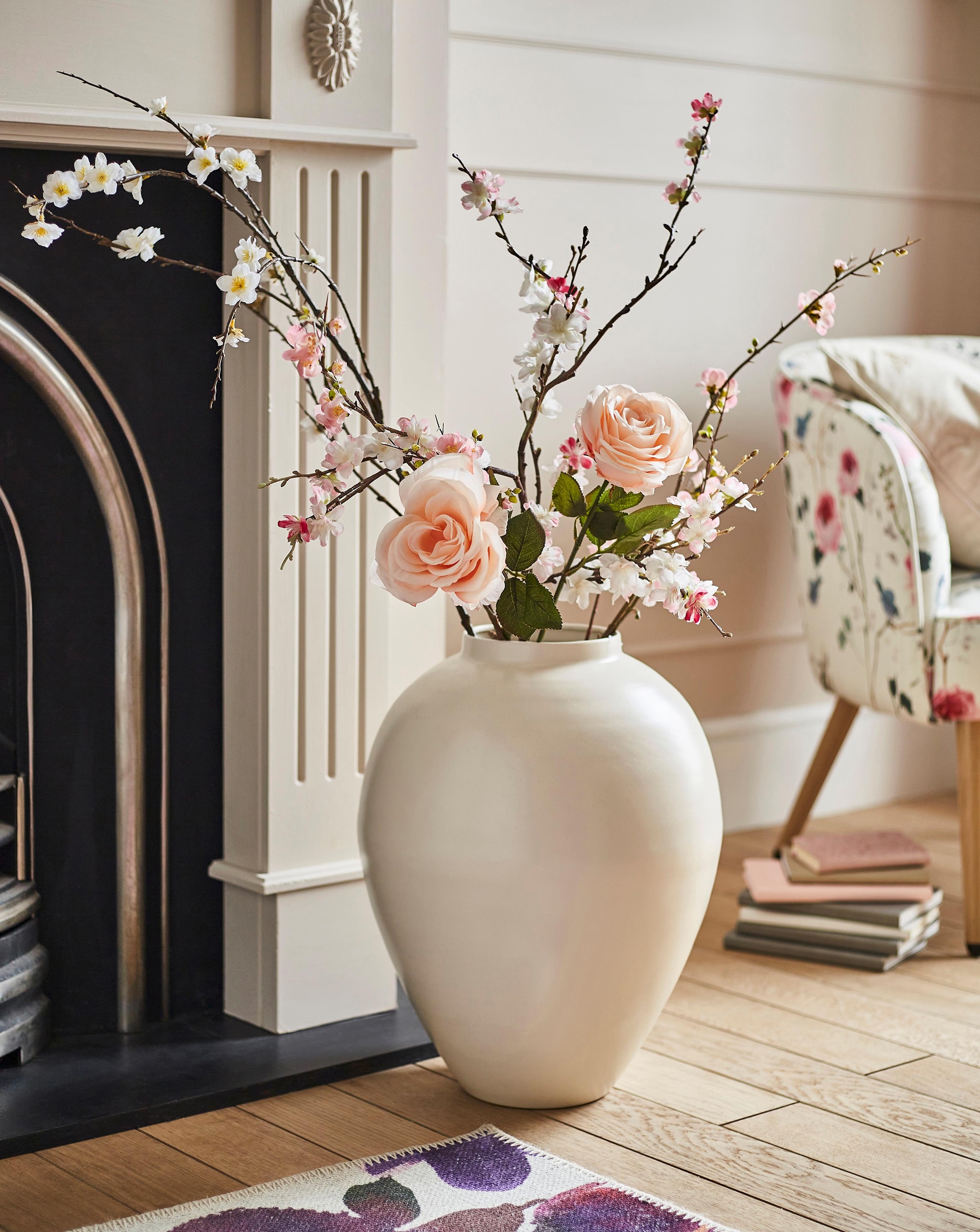 A cream vase in front of a fireplace